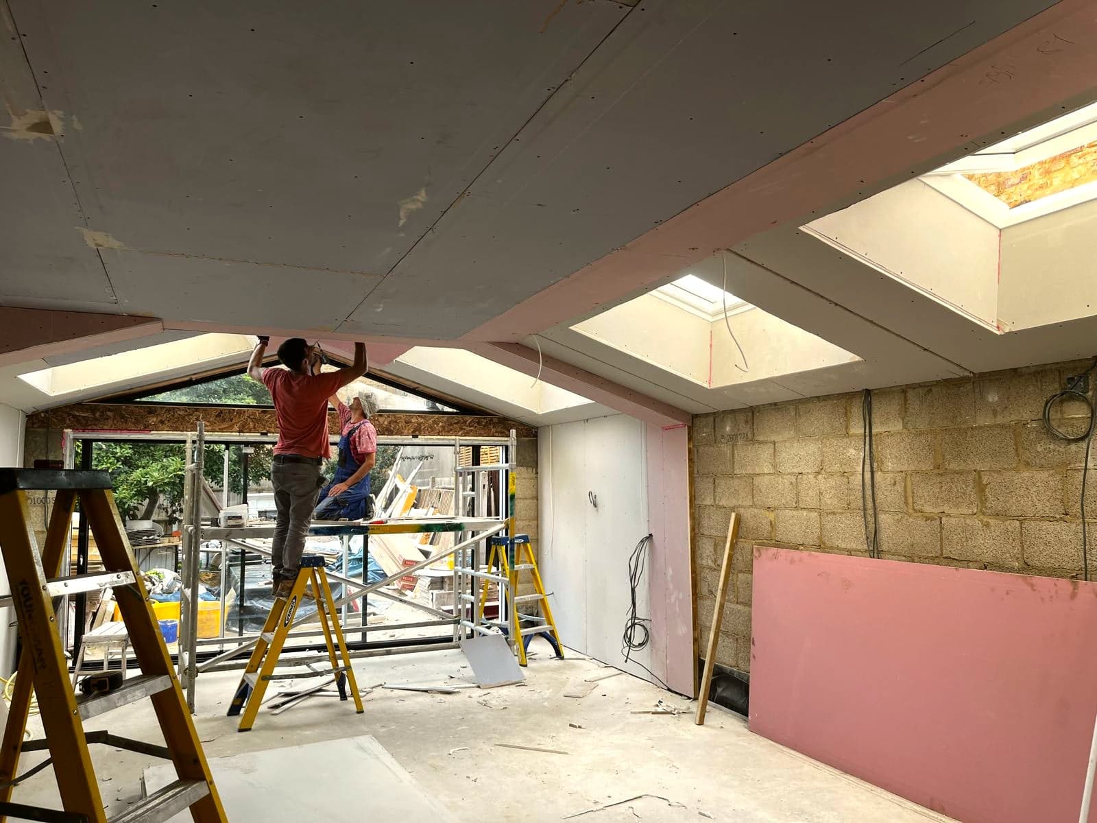 Ceiling plasterboard being fixed in a new extension, London