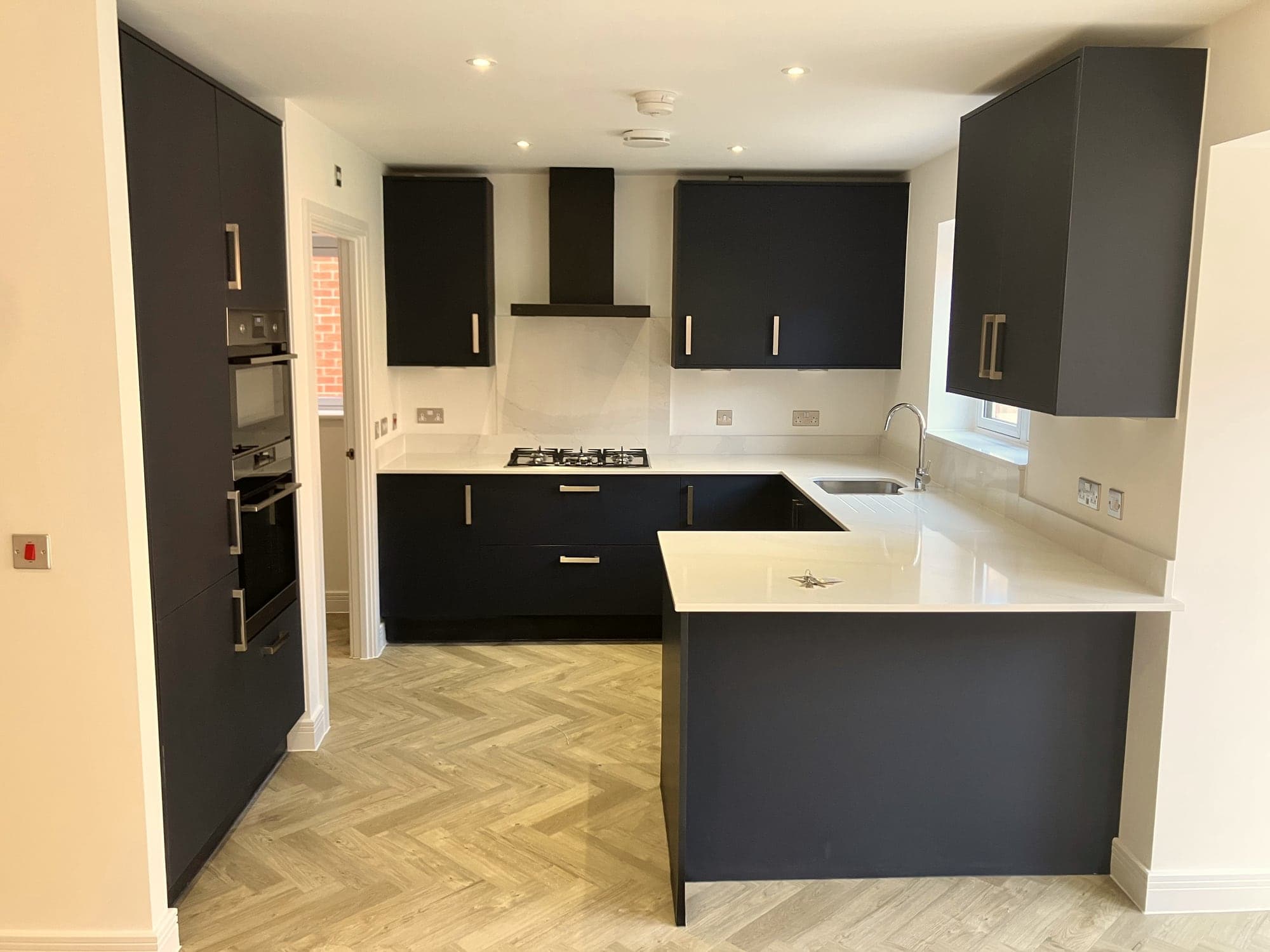 Navy kitchen with white quartz worktops and herringbone flooring, Hampstead NW3