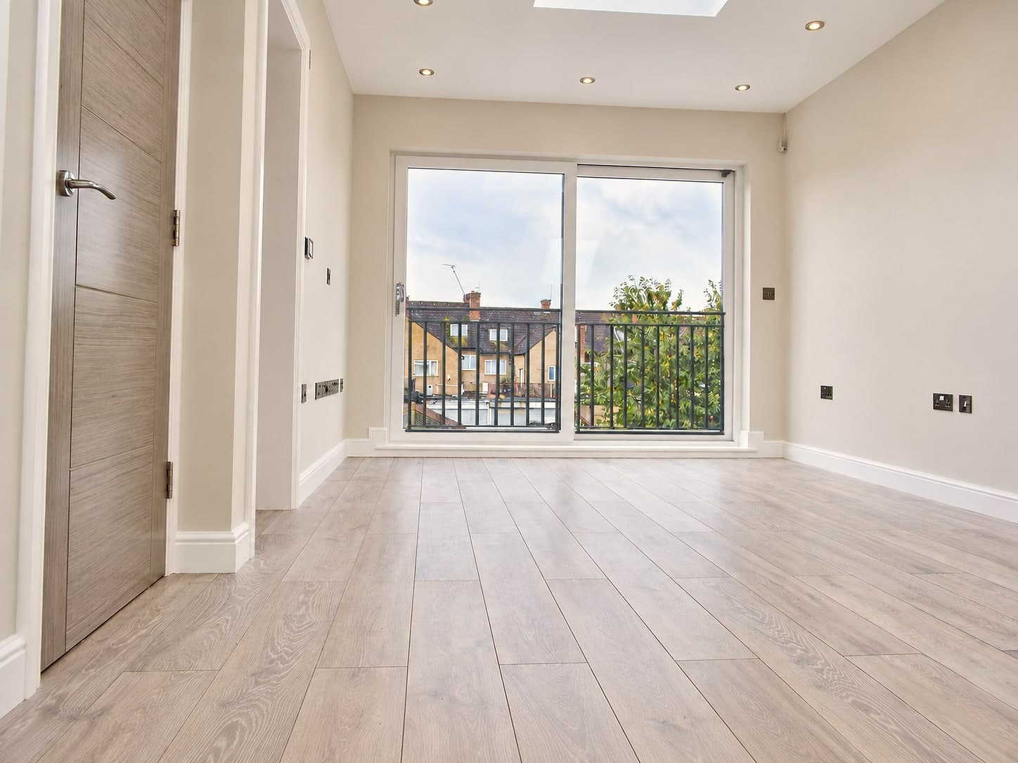 Finished loft conversion with full-height glazed doors onto a Juliet balcony and flush skylight