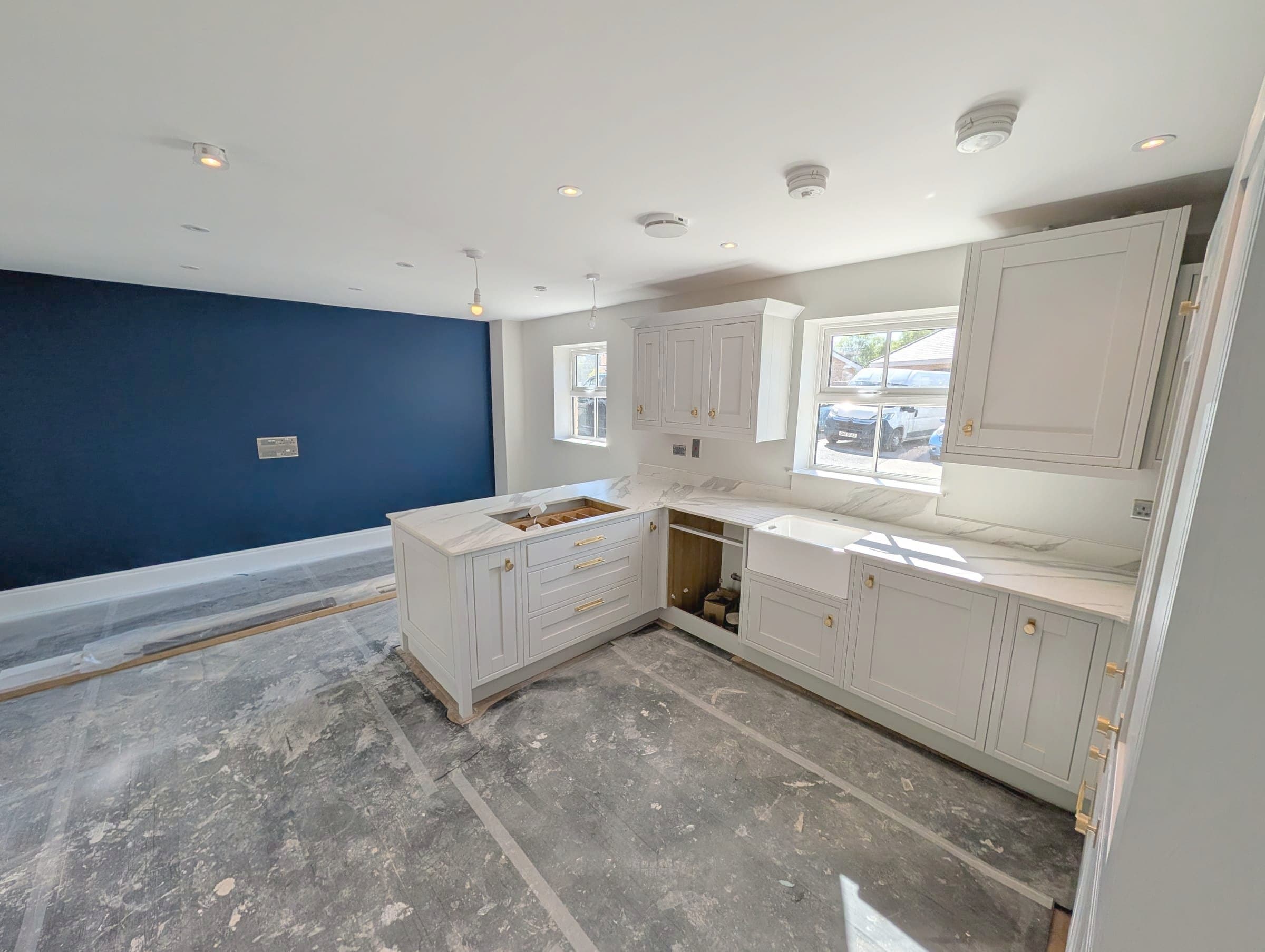 Shaker kitchen fitted with marble worktops and a navy feature wall, mid-refurbishment