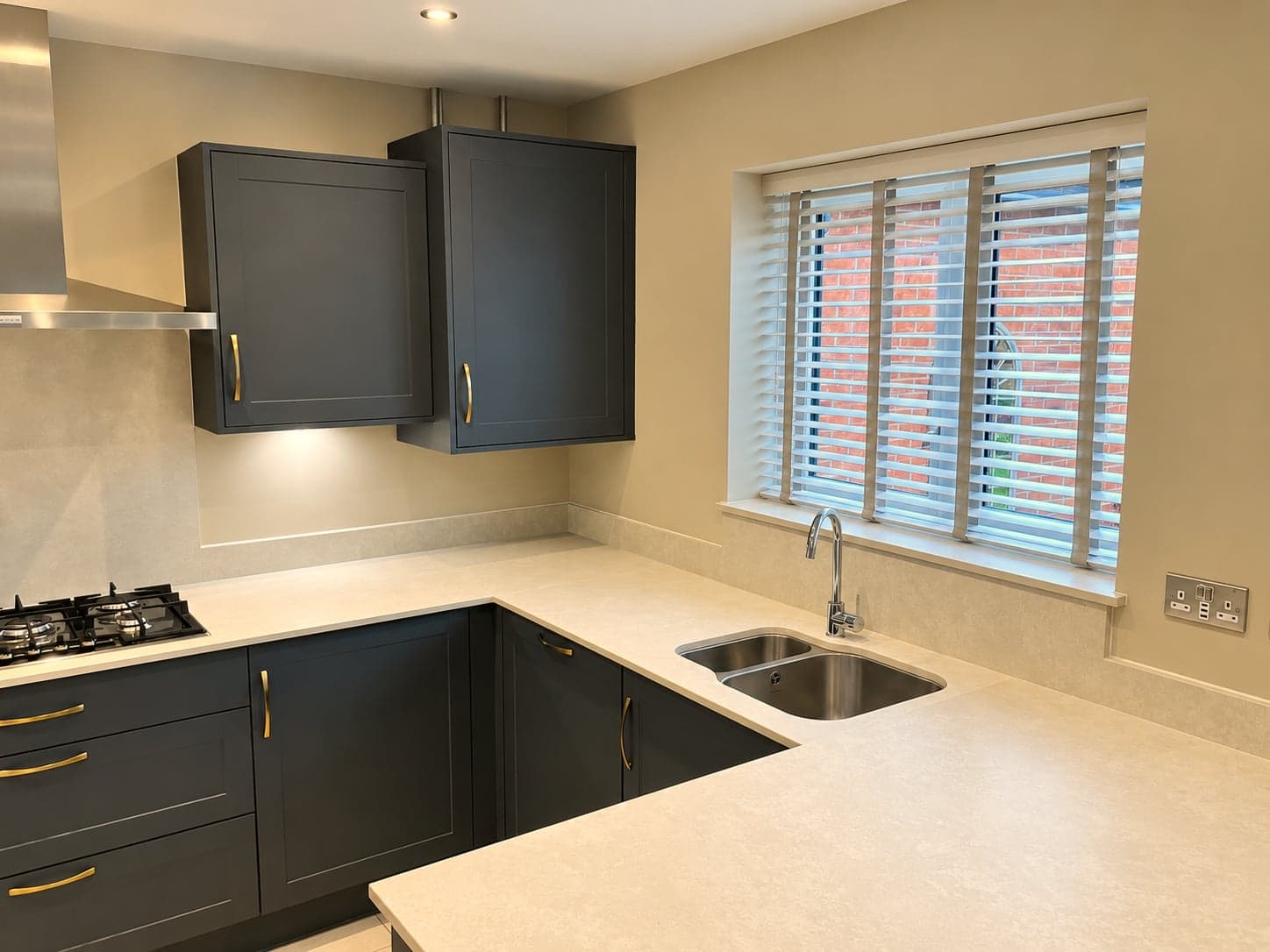 Hob and sink run under the shuttered window, brass handles on charcoal shaker doors, North Finchley N12