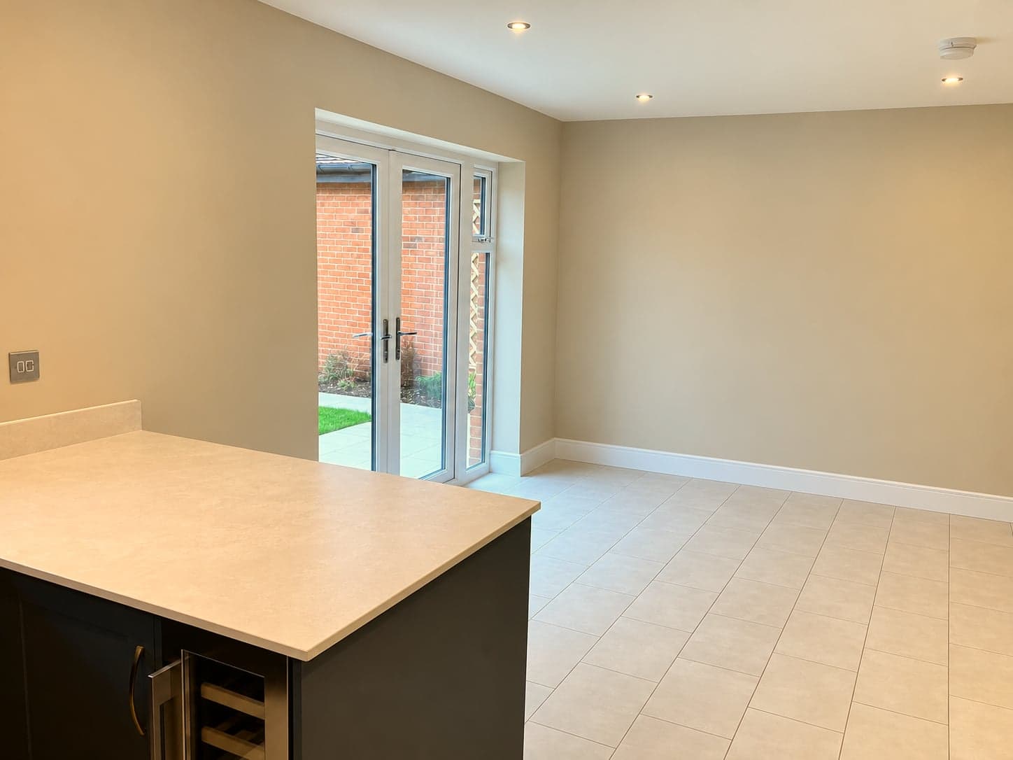Quartz peninsula with built-in wine cooler and French doors to the garden beyond, North Finchley N12
