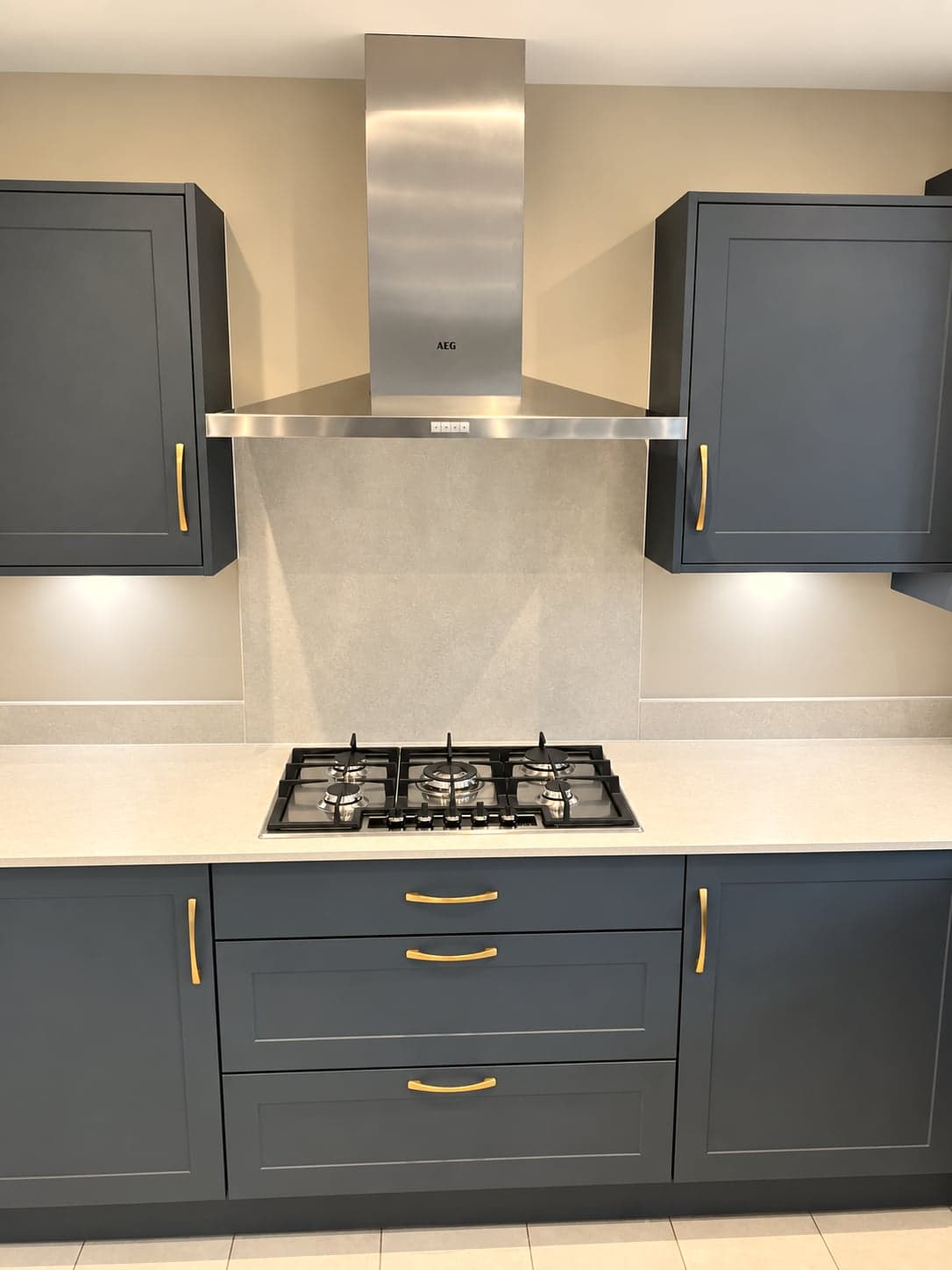 Stainless chimney extractor over the five-burner gas hob, brass handles below, North Finchley N12