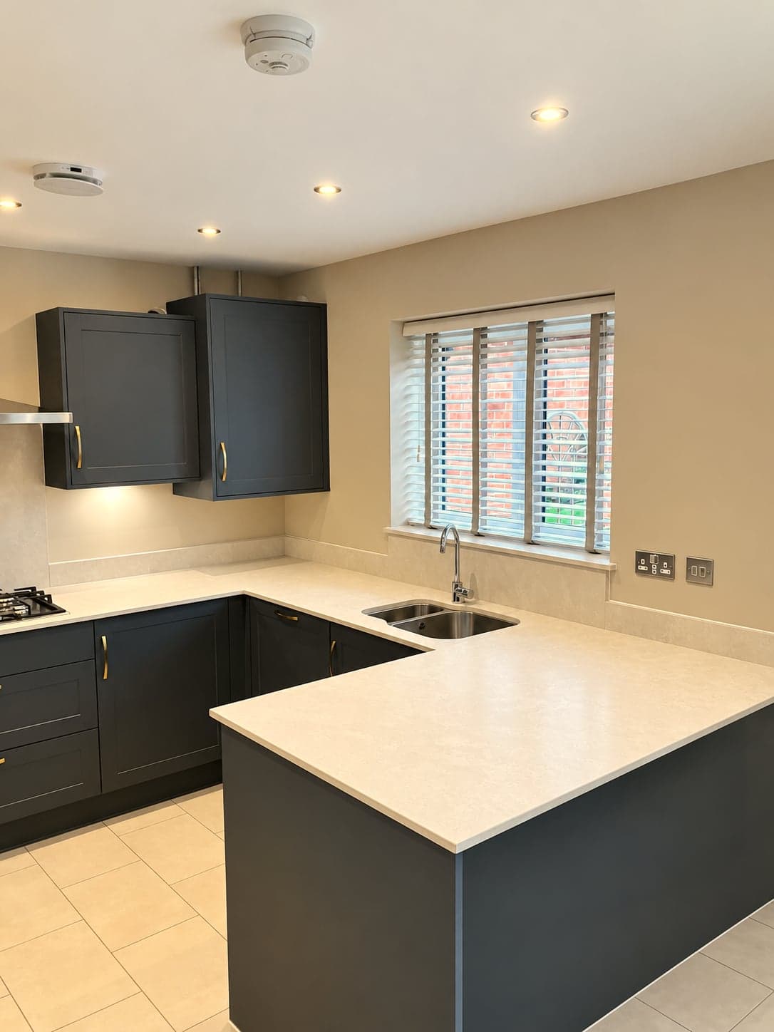Peninsula and sink under the shuttered window, quartz worktop wrapping the corner, North Finchley N12