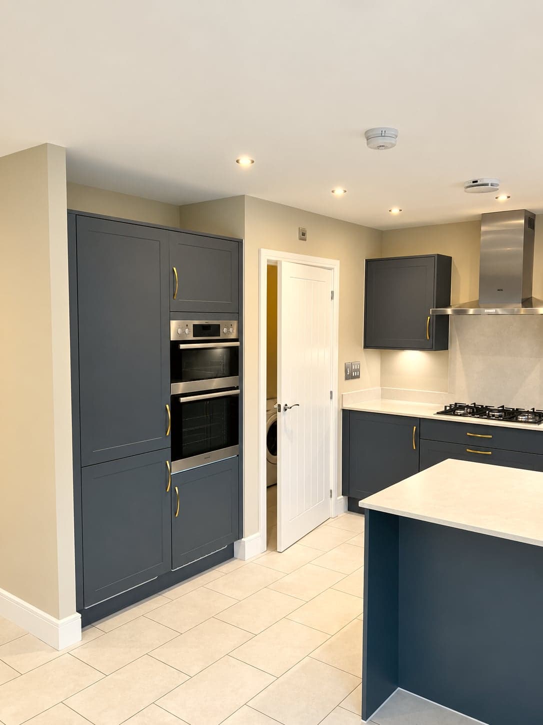 Kitchen from the hall: oven tower, hob run and peninsula in one view, North Finchley N12