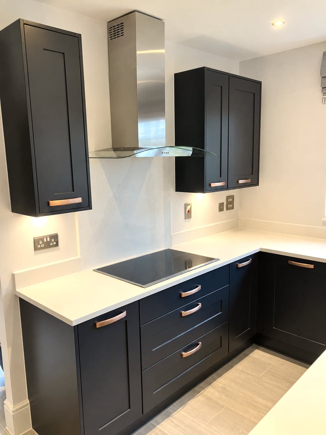 Induction hob under the stainless chimney extractor with charcoal wall units either side, Notting Hill W11