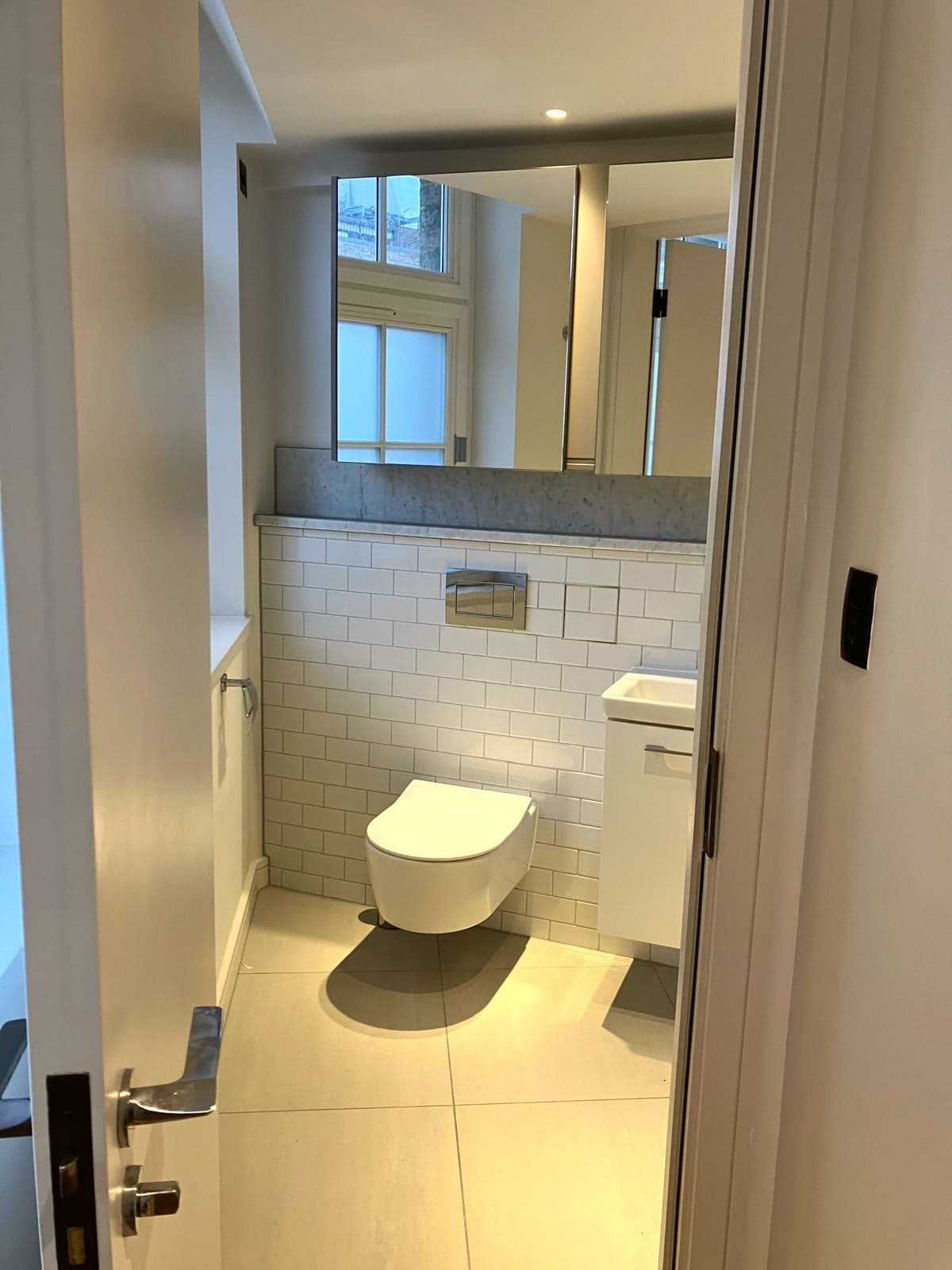 Bathroom seen through the open door with the mirror and vanity beyond, Camden NW1
