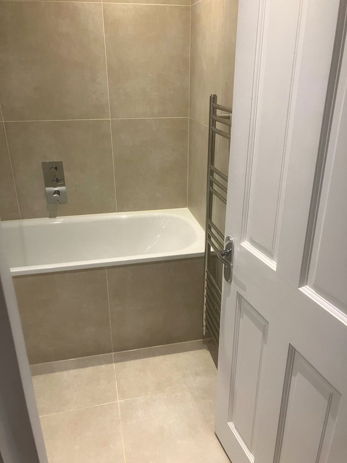 Bath with wall-mounted filler and chrome towel rail beside the panelled door, Streatham Hill SW2