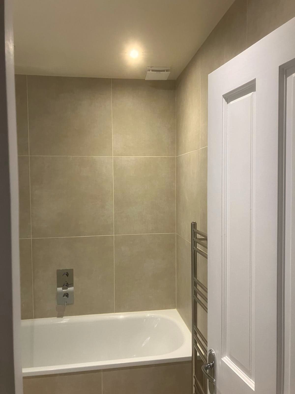 Bath and heated towel rail against large-format stone-effect tiling, Streatham Hill SW2