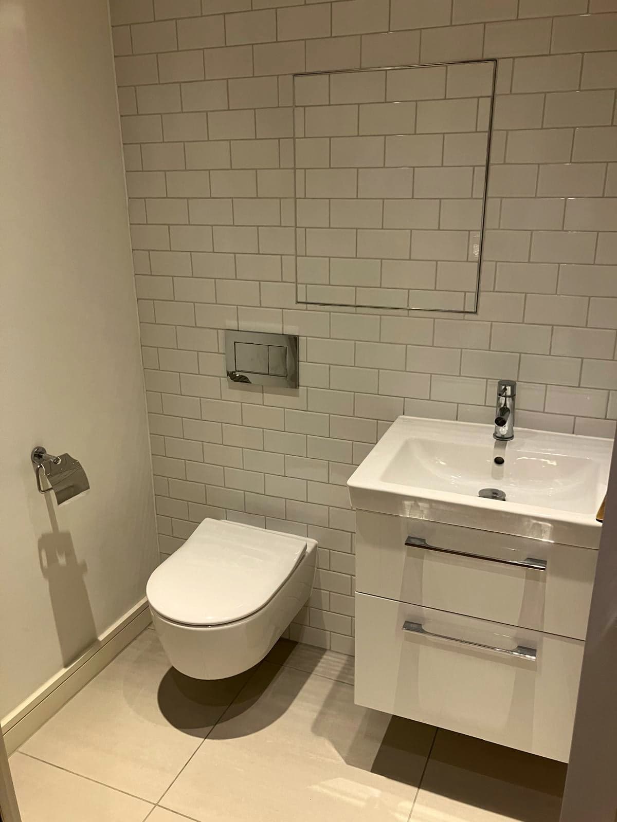 Wall-hung vanity and concealed-cistern WC against white metro tiling, Marylebone W1
