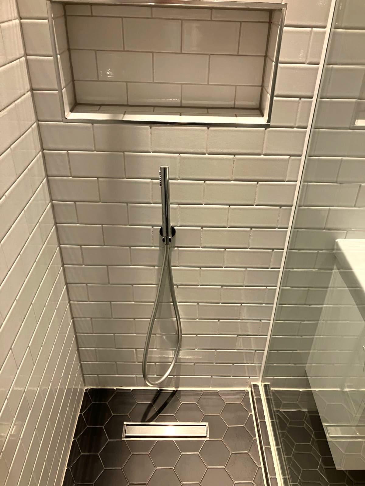 Shower enclosure from above: linear drain, hexagonal floor tiles and handset, Marylebone W1