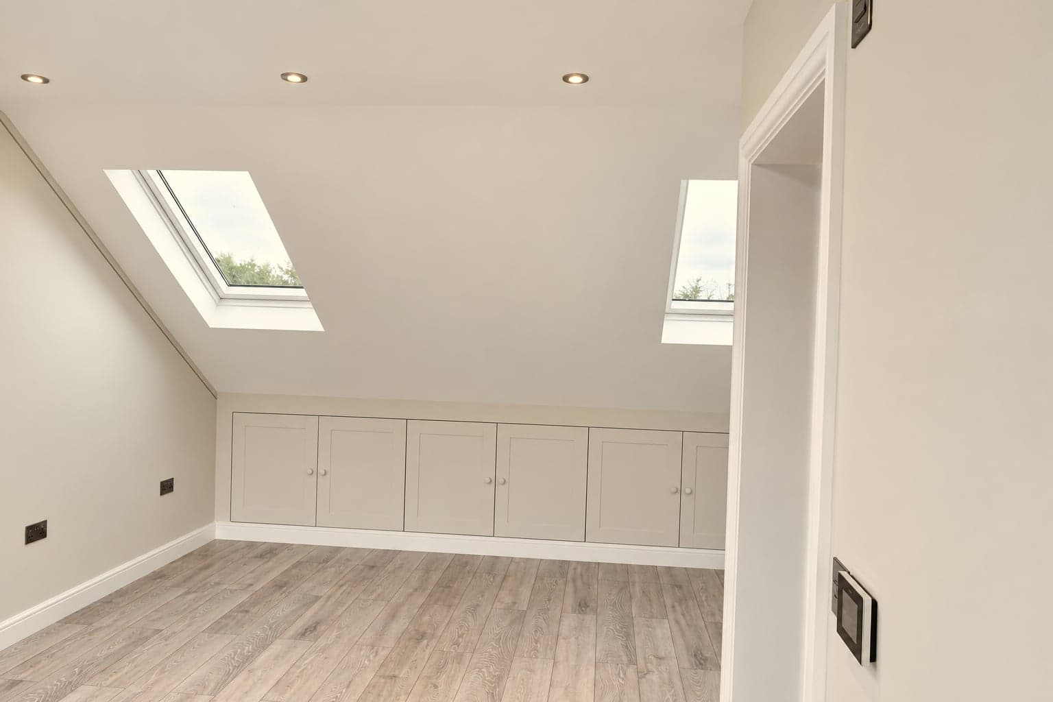 Sloping ceiling with two roof windows above a run of built-in eaves cupboards, Hampstead NW3