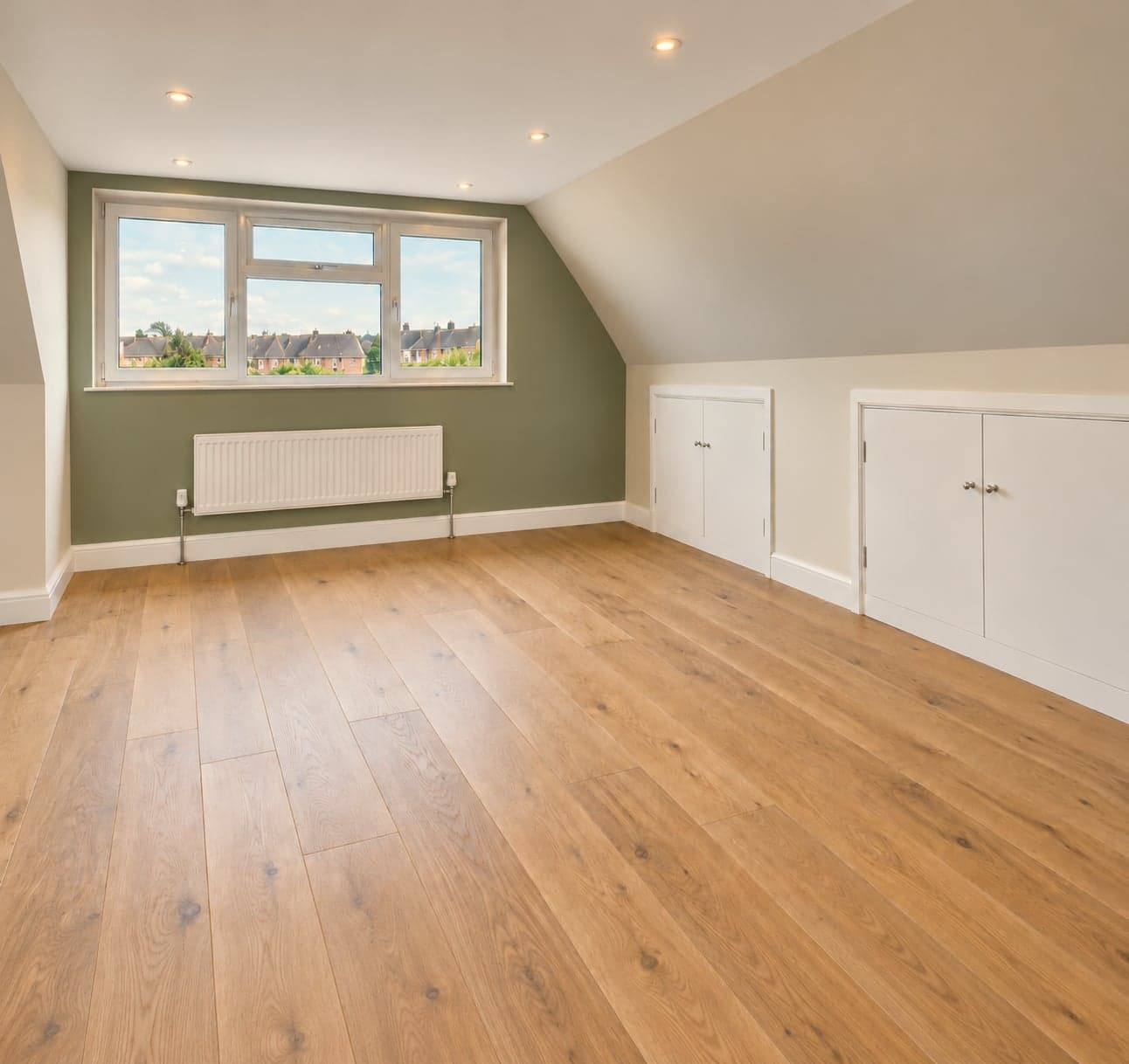 Loft bedroom with tall dormer window, green feature wall and oak flooring, dormer loft conversion in Watford WD17