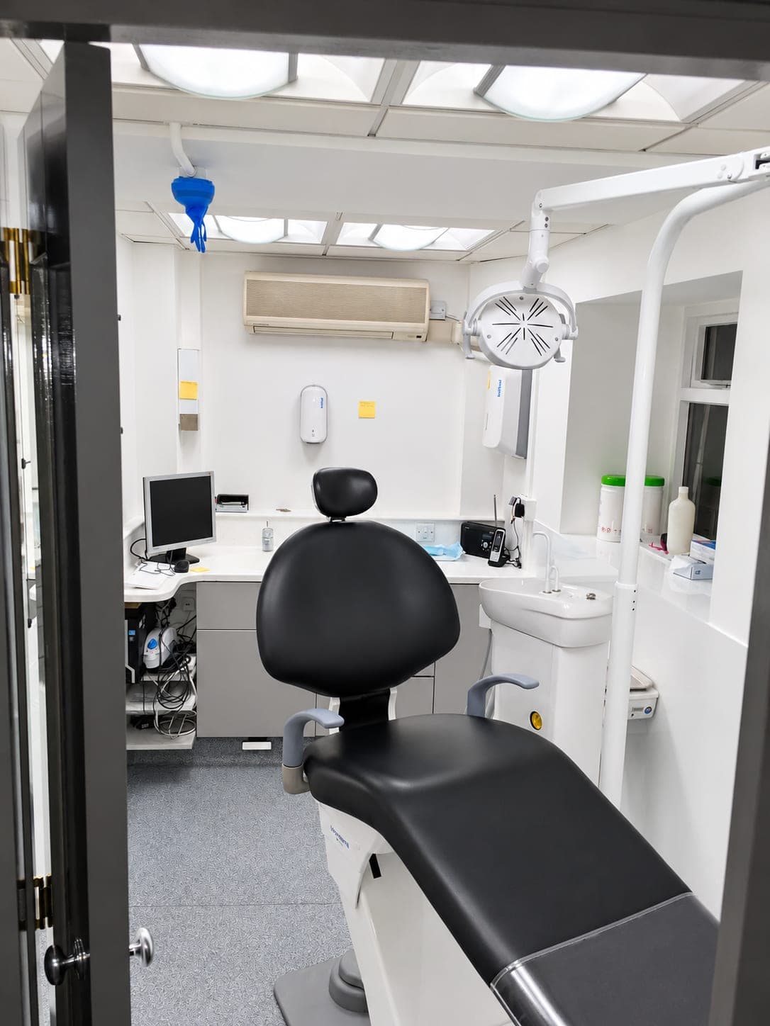 Refurbished white dental surgery with black chair, air conditioning and clinical worktop, Finchley N3