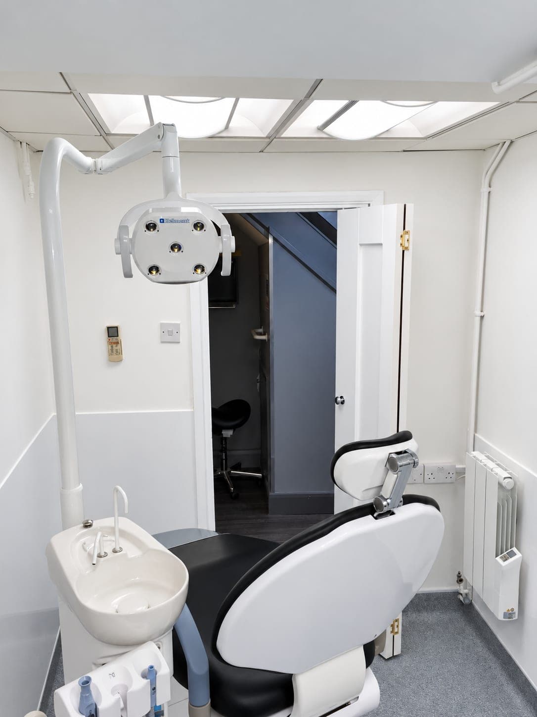 Surgery from the doorway: dental chair, spittoon and overhead light against new white walls, Finchley N3