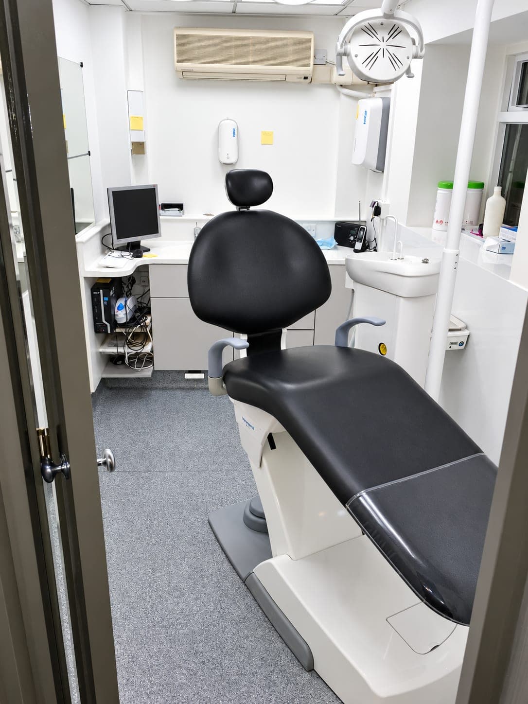 Treatment room with chair, monitor arm and wall-mounted dispensers above the worktop, Finchley N3