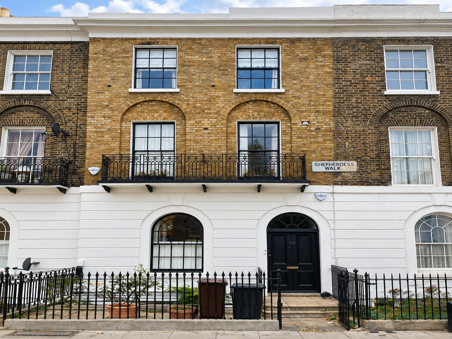 Restored Georgian terrace facade with white stucco ground floor, yellow stock brick above and black railings, Shepherdess Walk N1