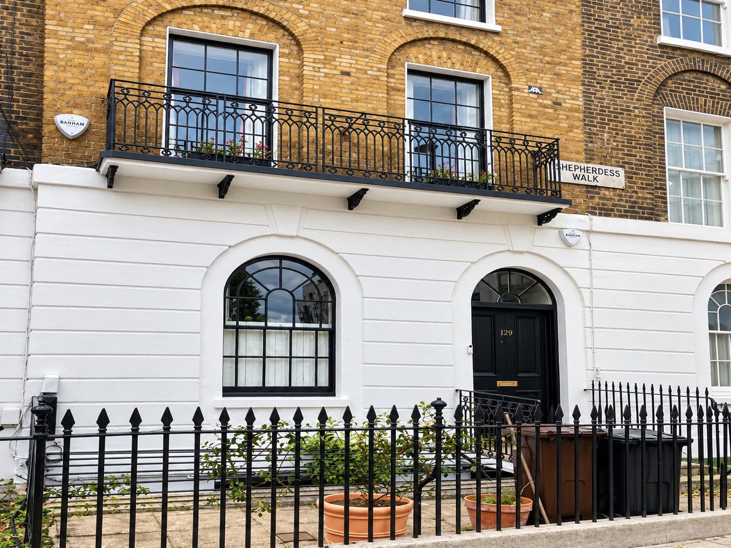 Arched front door and windows set into the repaired stucco, Shepherdess Walk N1
