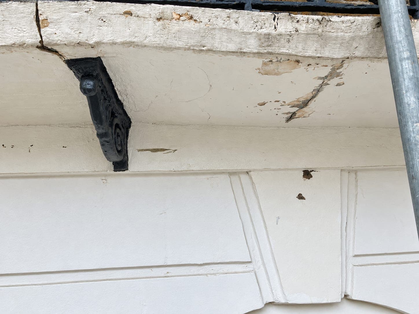 Cracked and blown stucco at the balcony bracket before repair, Shepherdess Walk N1