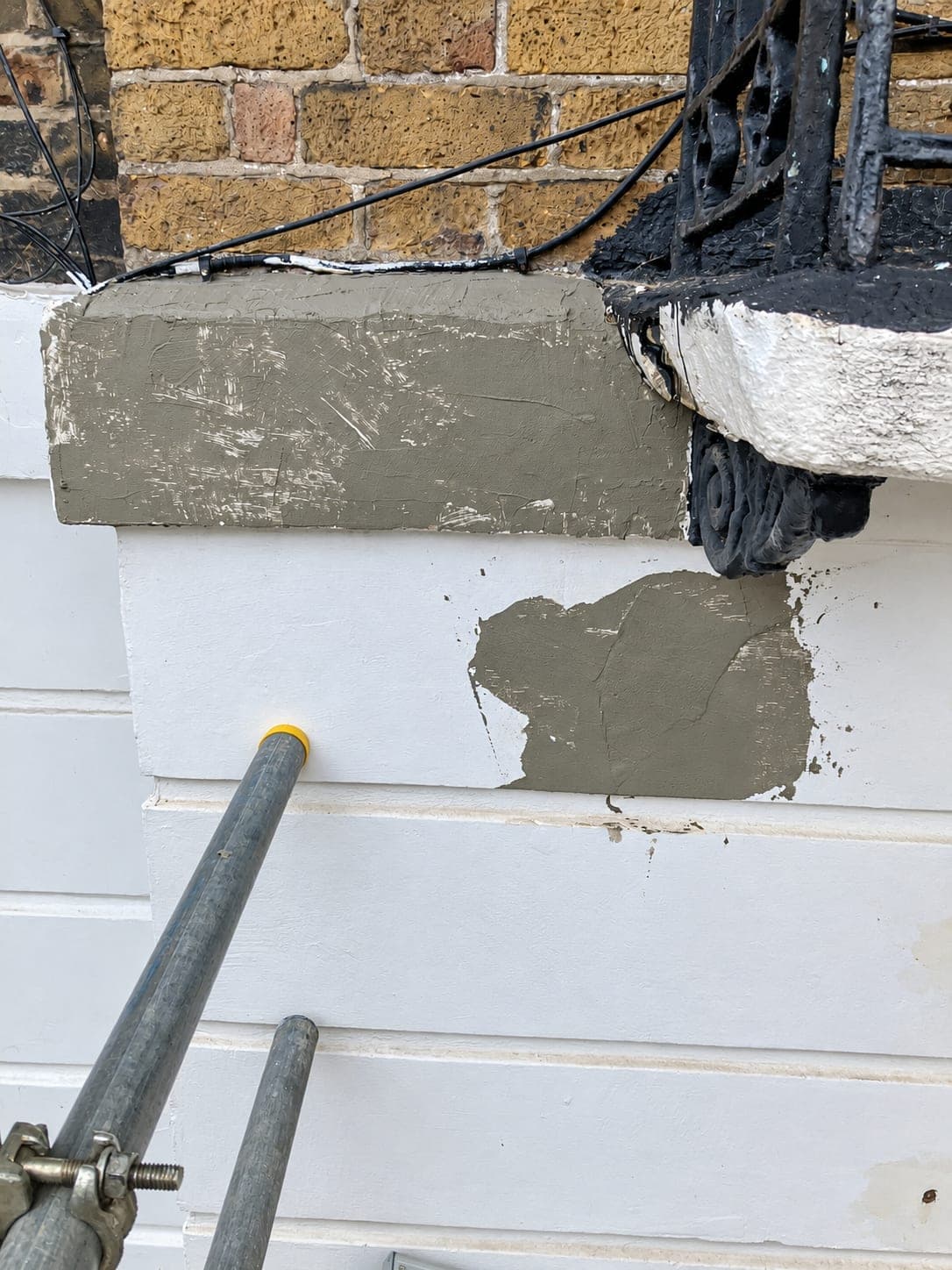 Repair patch beneath the balcony bracket before painting, Shepherdess Walk N1