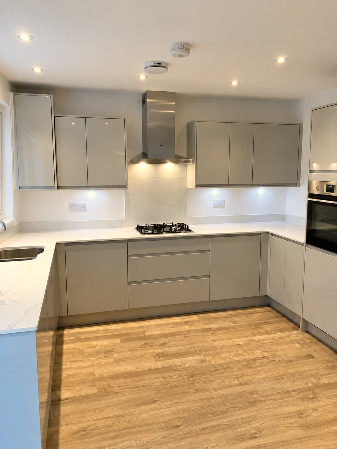 Handleless gloss units and quartz peninsula with the chimney extractor over the hob, Hampstead NW3