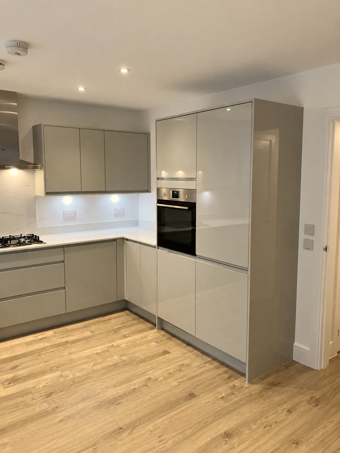 Gloss slab doors and quartz worktop with the tall oven housing alongside, Hampstead NW3