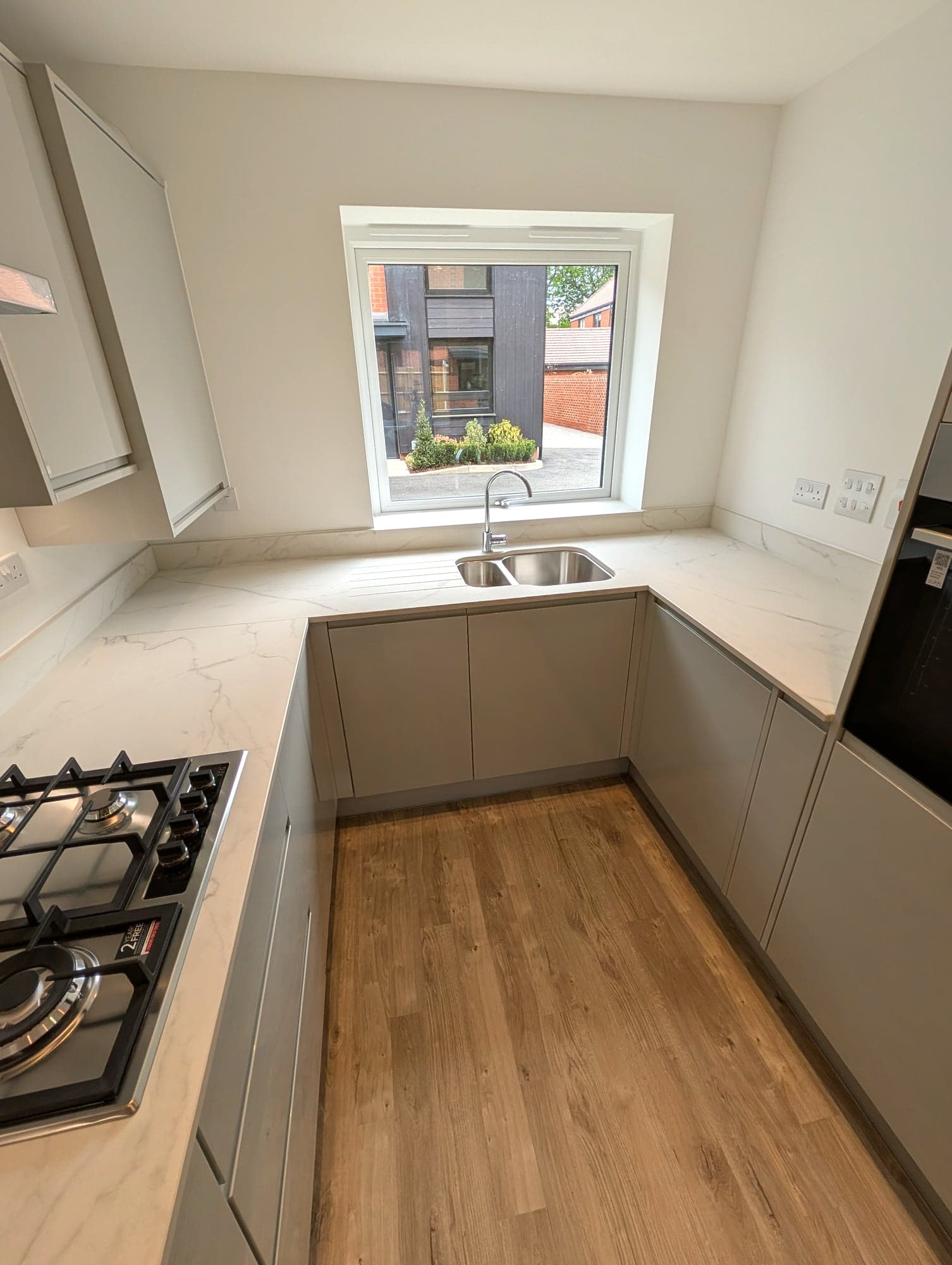 Inset sink and marble-effect worktop wrapping the corner under the window, Barnet EN5