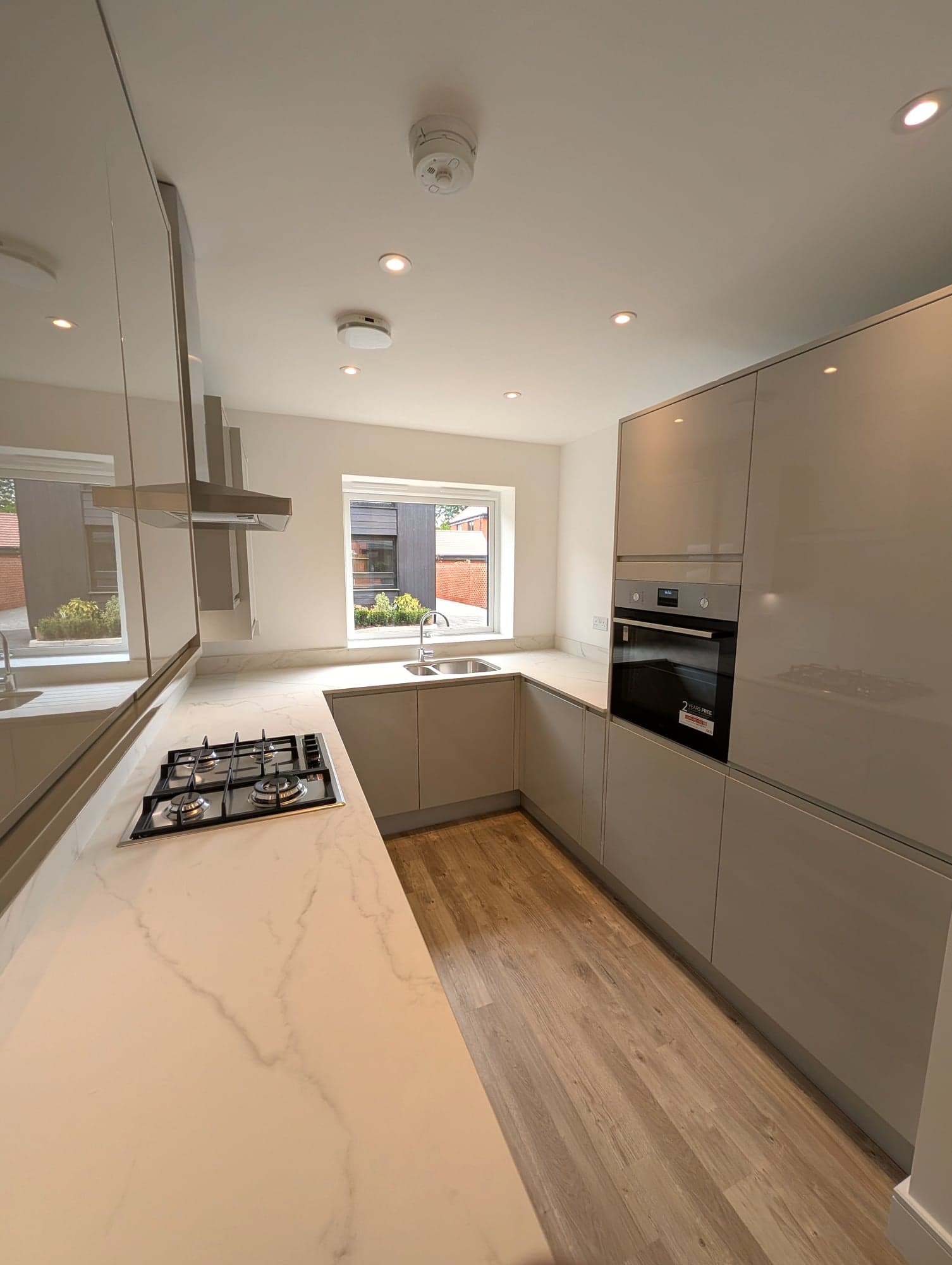 Handleless units and marble-effect worktop looking down the galley, Barnet EN5