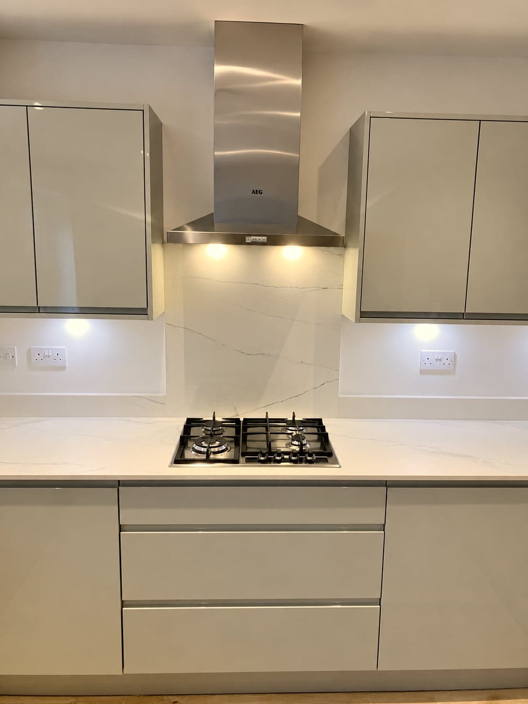 Gas hob below the stainless chimney extractor with marble-effect splashback, Battersea SW11