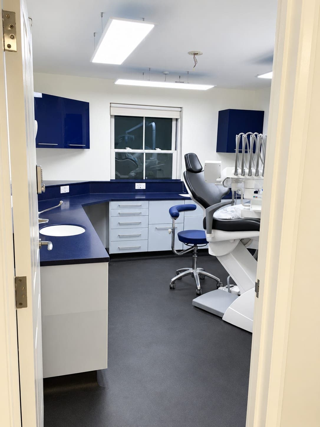 Dental surgery fit-out with navy seamless worktops, white cabinetry and dental chair, Haverhill CB9