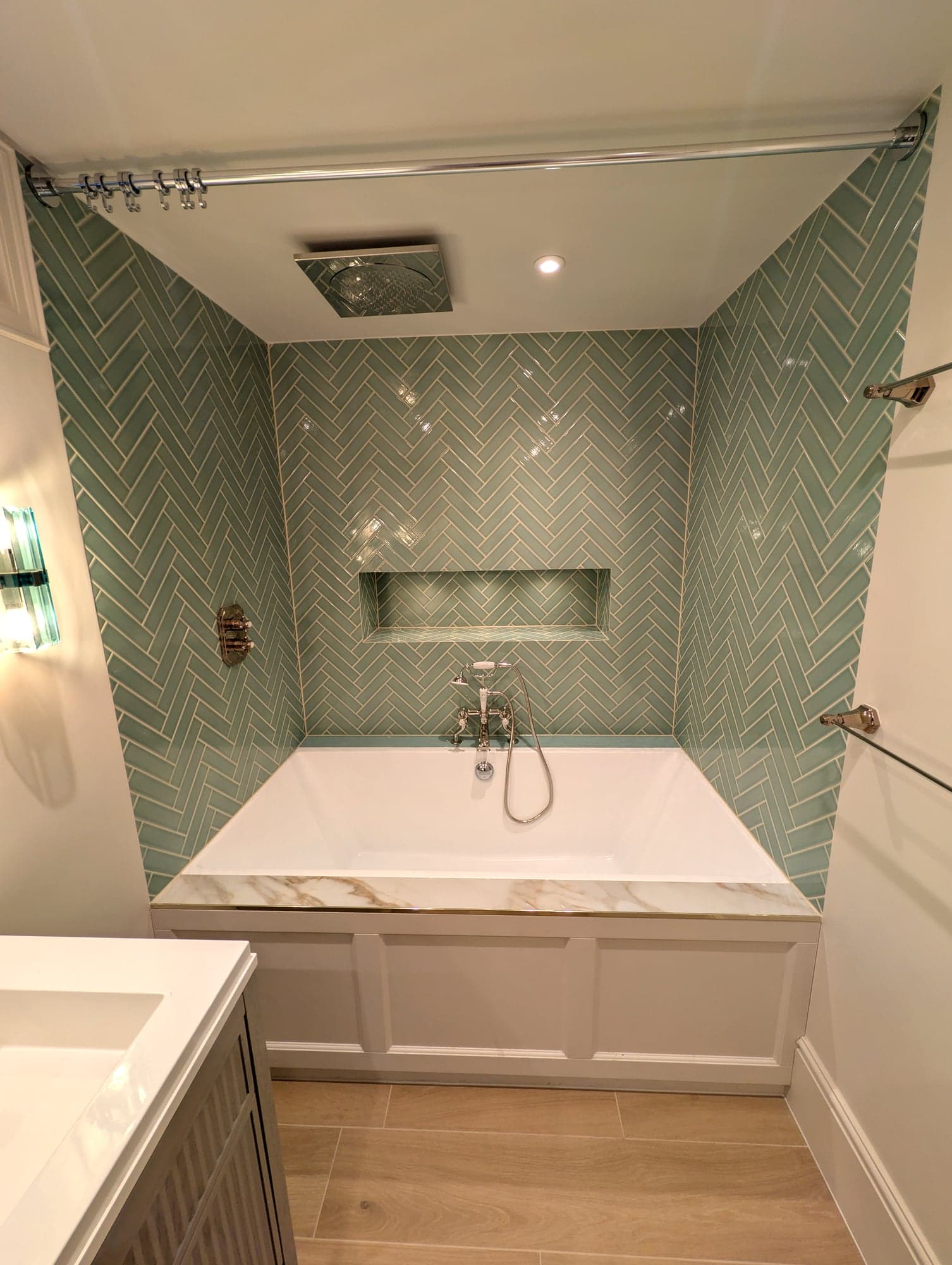 Bath alcove with shower rail, recessed niche and sage herringbone tiling, Fulham SW6