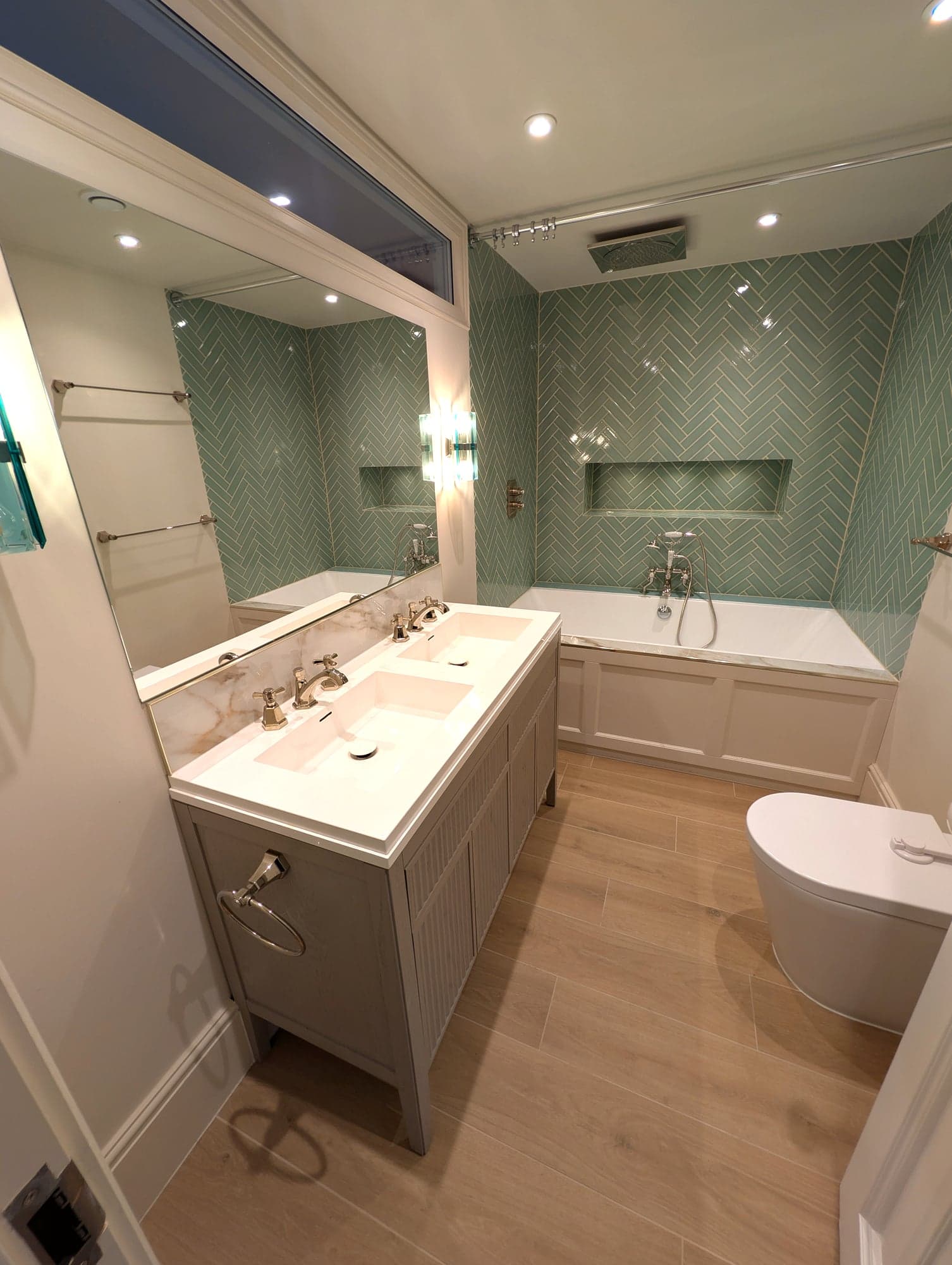 Angled view of the vanity, bath and WC with the mirror reflecting the herringbone tiling, Fulham SW6