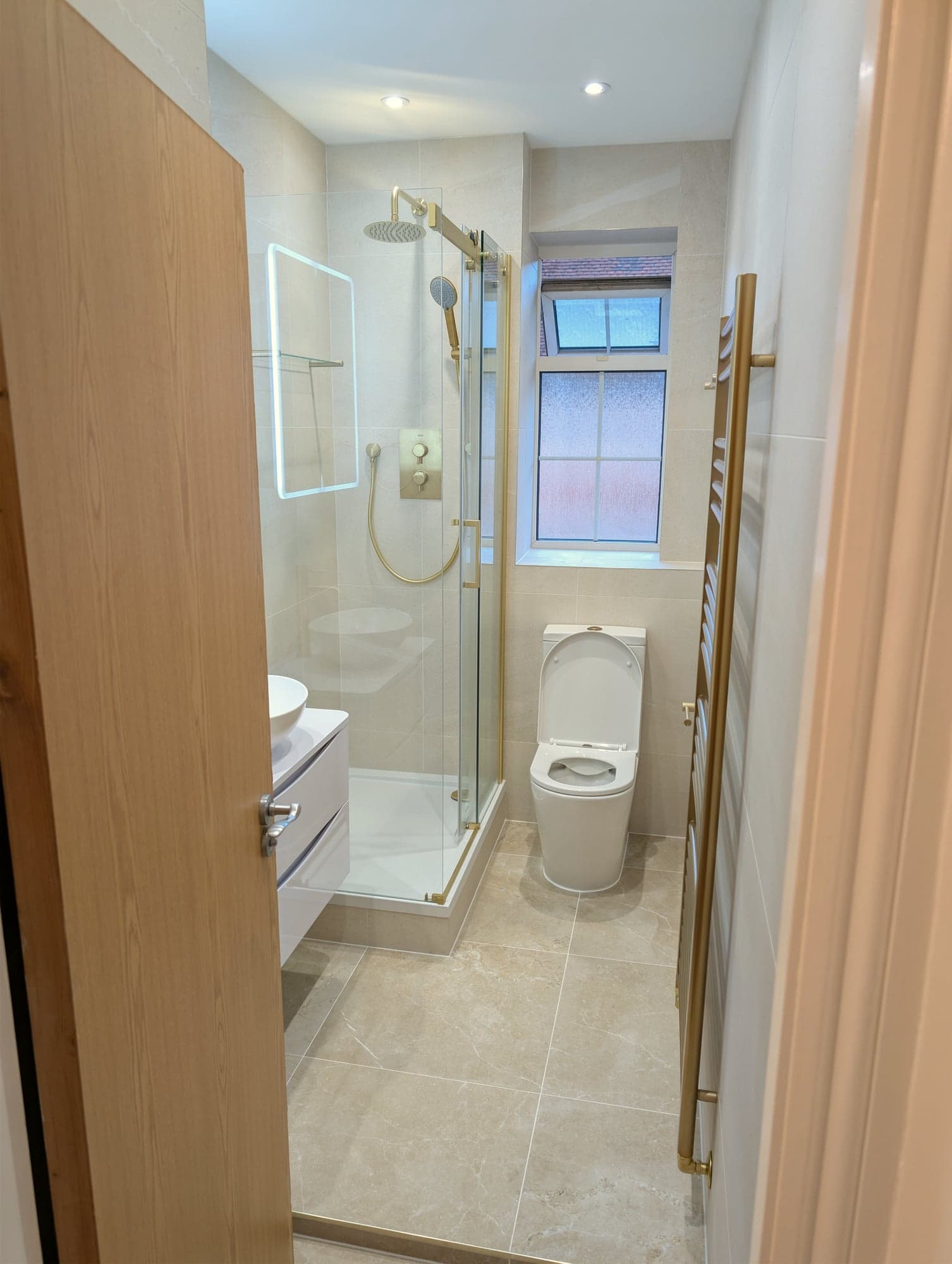 Bathroom with brushed brass fittings, countertop basin and walk-in shower in large-format stone-effect tiling, Nine Elms SW8