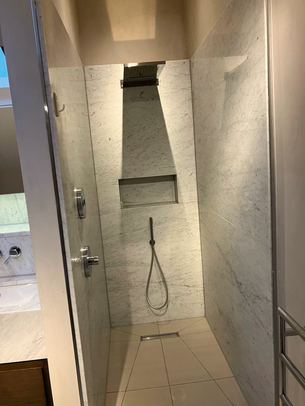 Walk-in shower lined in Carrara marble with a recessed niche and linear drain, South Kensington SW7