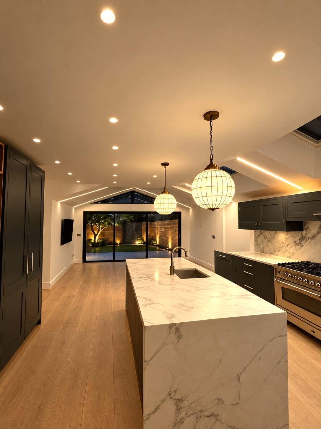 Open-plan kitchen extension from the far end, island, dark units and glazed rear wall, St Albans AL1