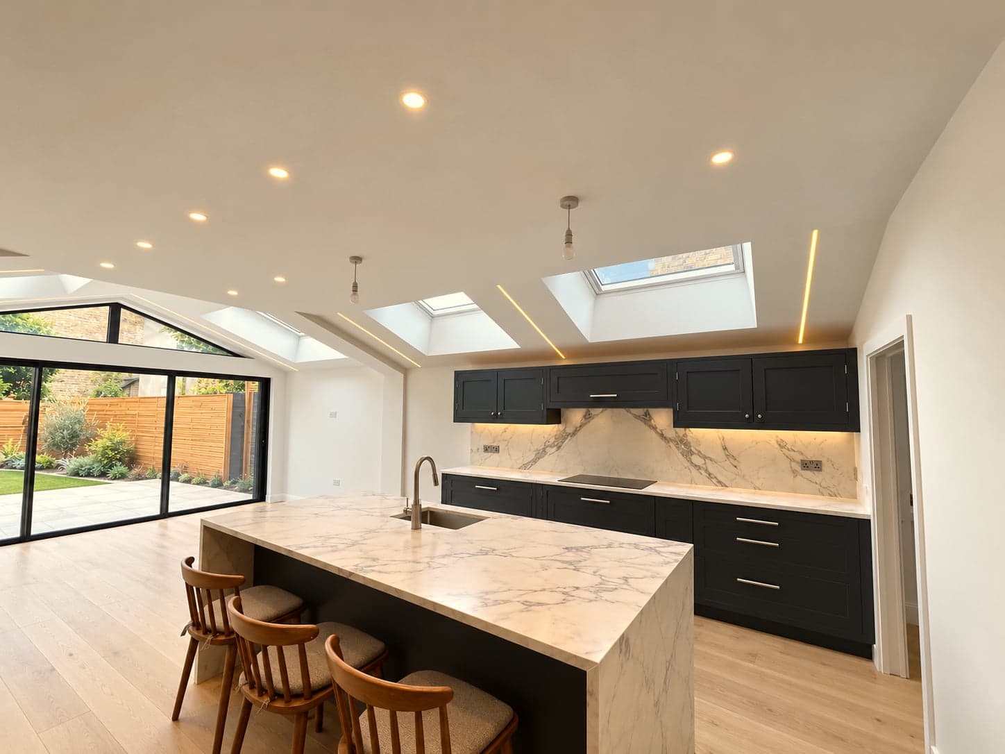 Marble island with bar stools, dark cabinetry and bi-fold doors to the garden, St Albans AL1