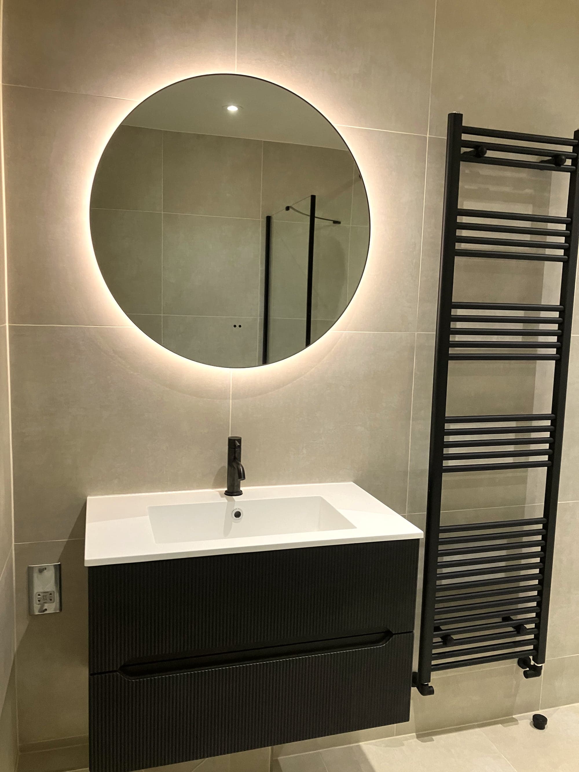 Ribbed black vanity with countertop basin under the illuminated round mirror, Clapham Common SW4
