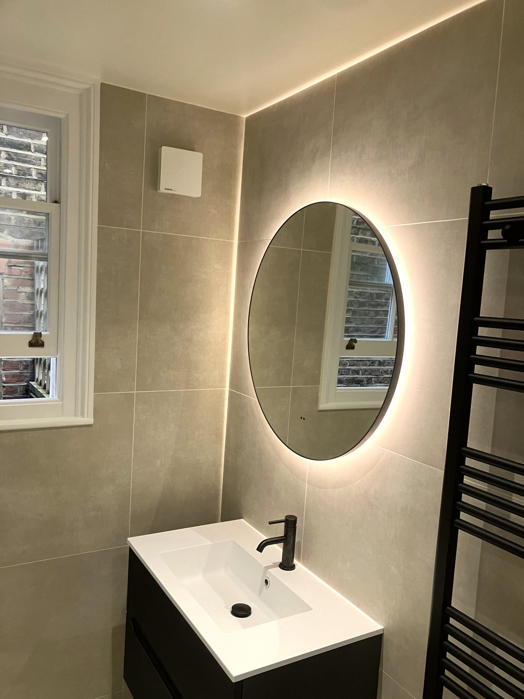 Backlit round mirror, matte black vanity and heated towel rail, Clapham Common SW4