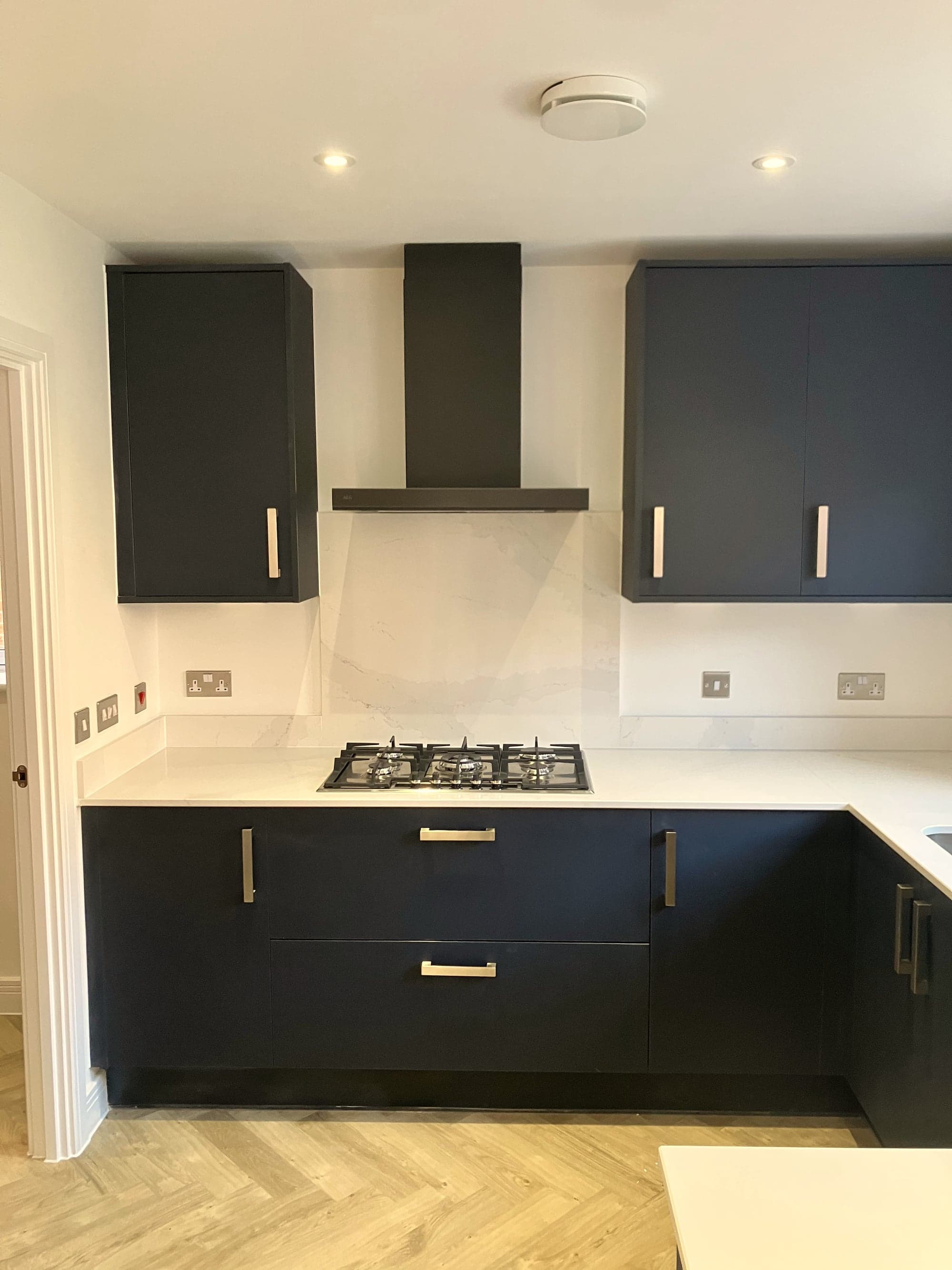 Gas hob under the chimney extractor with navy units either side, Hampstead NW3
