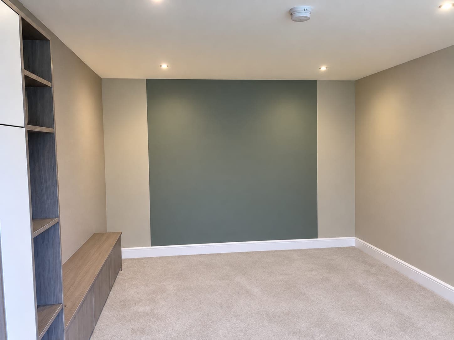 Living room with a sage green feature wall and textured wallcovering, London