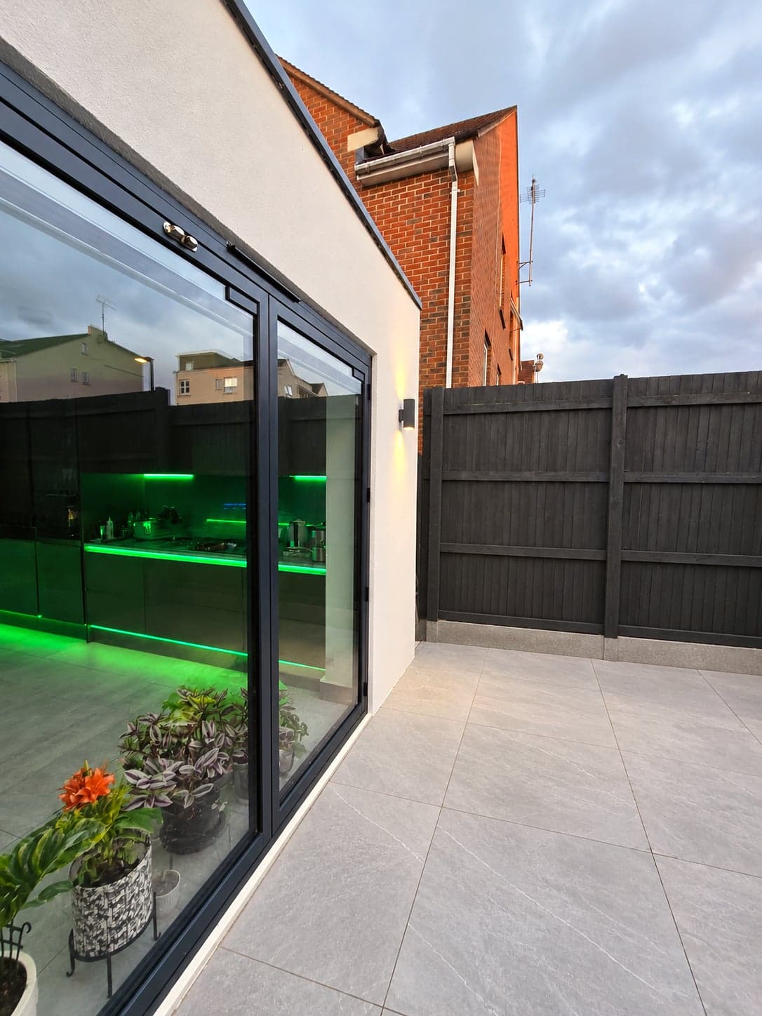 Glazed rear wall lit from inside, showing the green-lit kitchen beyond, High Barnet EN5