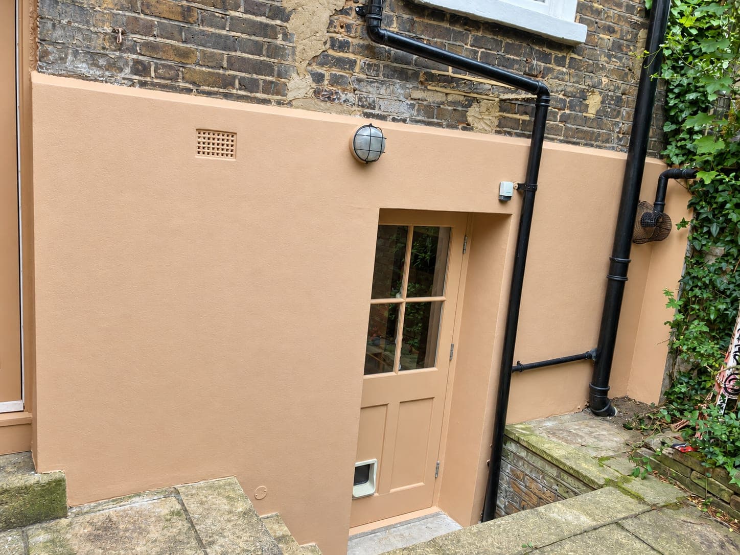 Rendered wall and soil pipe run with the render cut neatly around it, Hammersmith W6