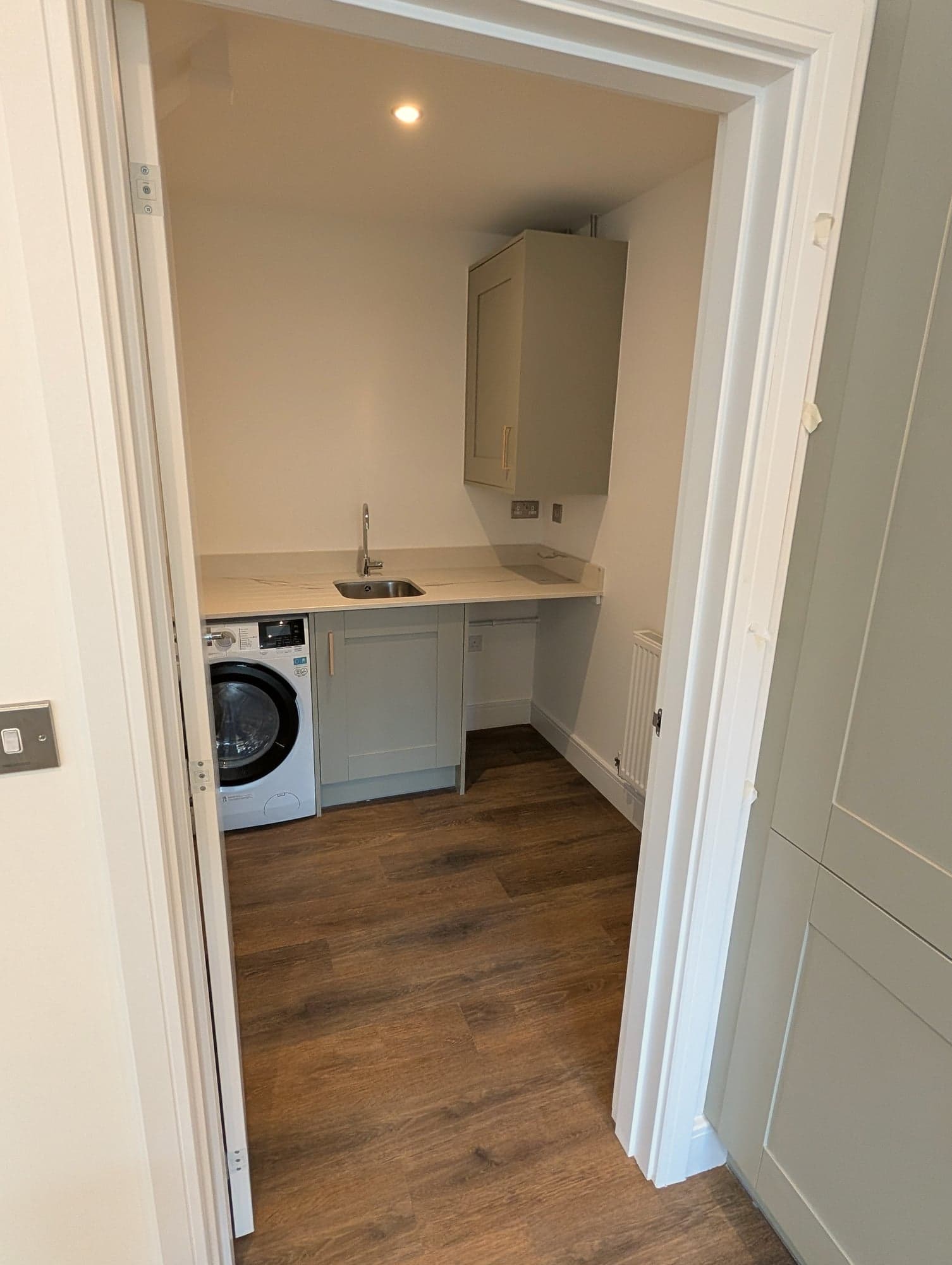 Utility room with sink, worktop and washing machine seen through the doorway, Chiswick W4