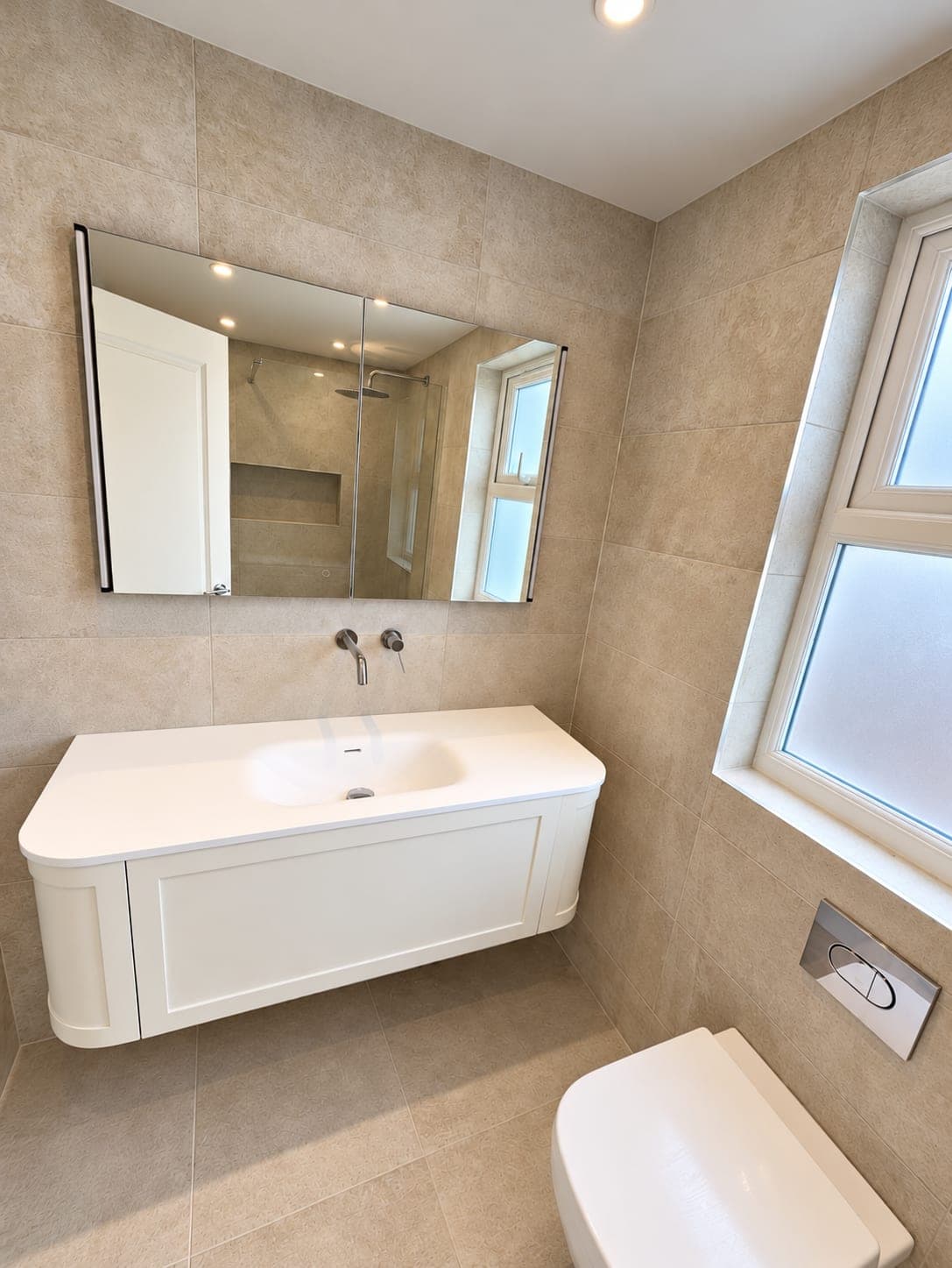 Wall-hung vanity and WC with stone-effect porcelain tiling and a frosted window, St John's Wood NW8