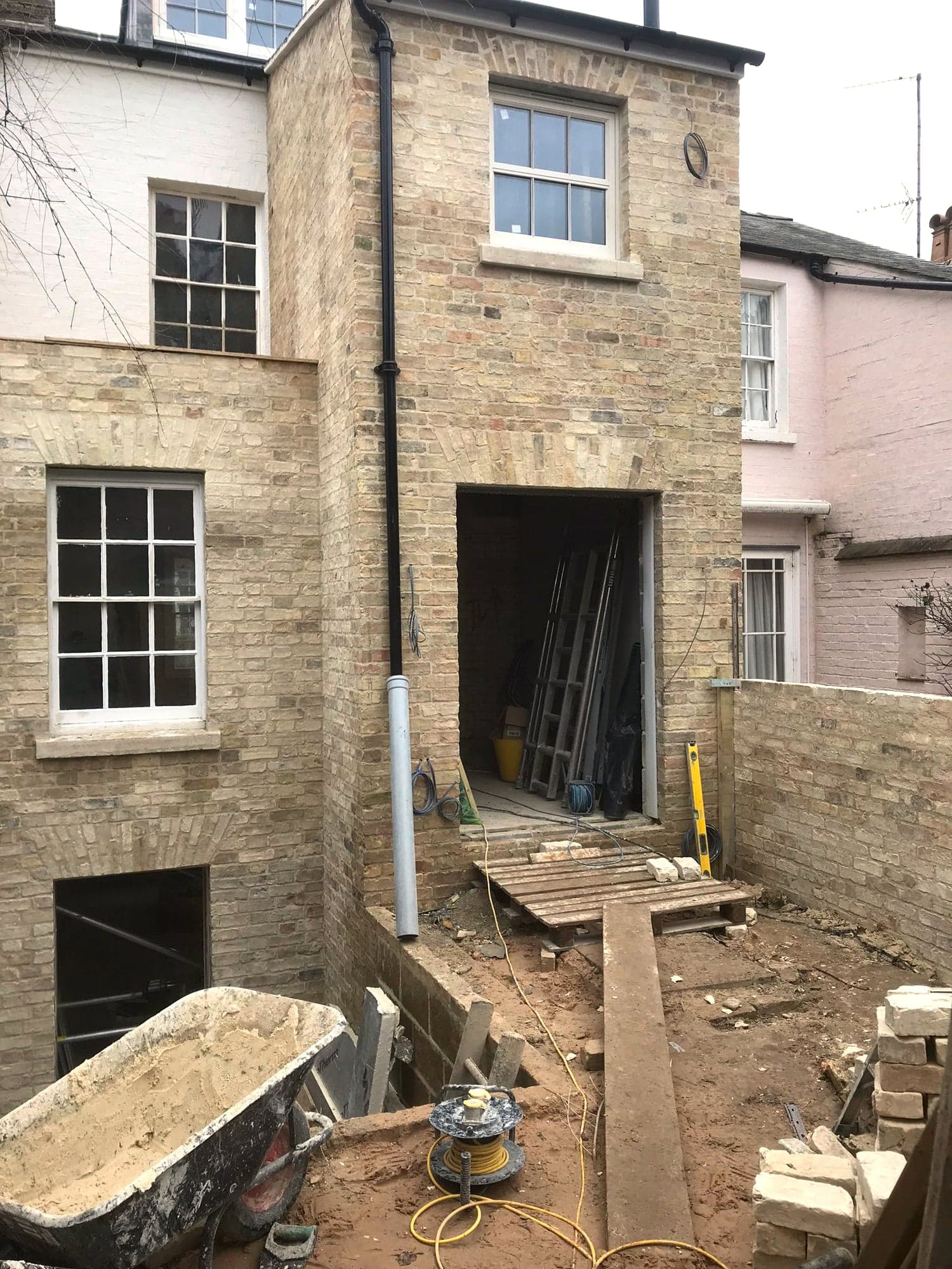Lower ground opening formed, with spoil and materials still in the courtyard, Kensington W8