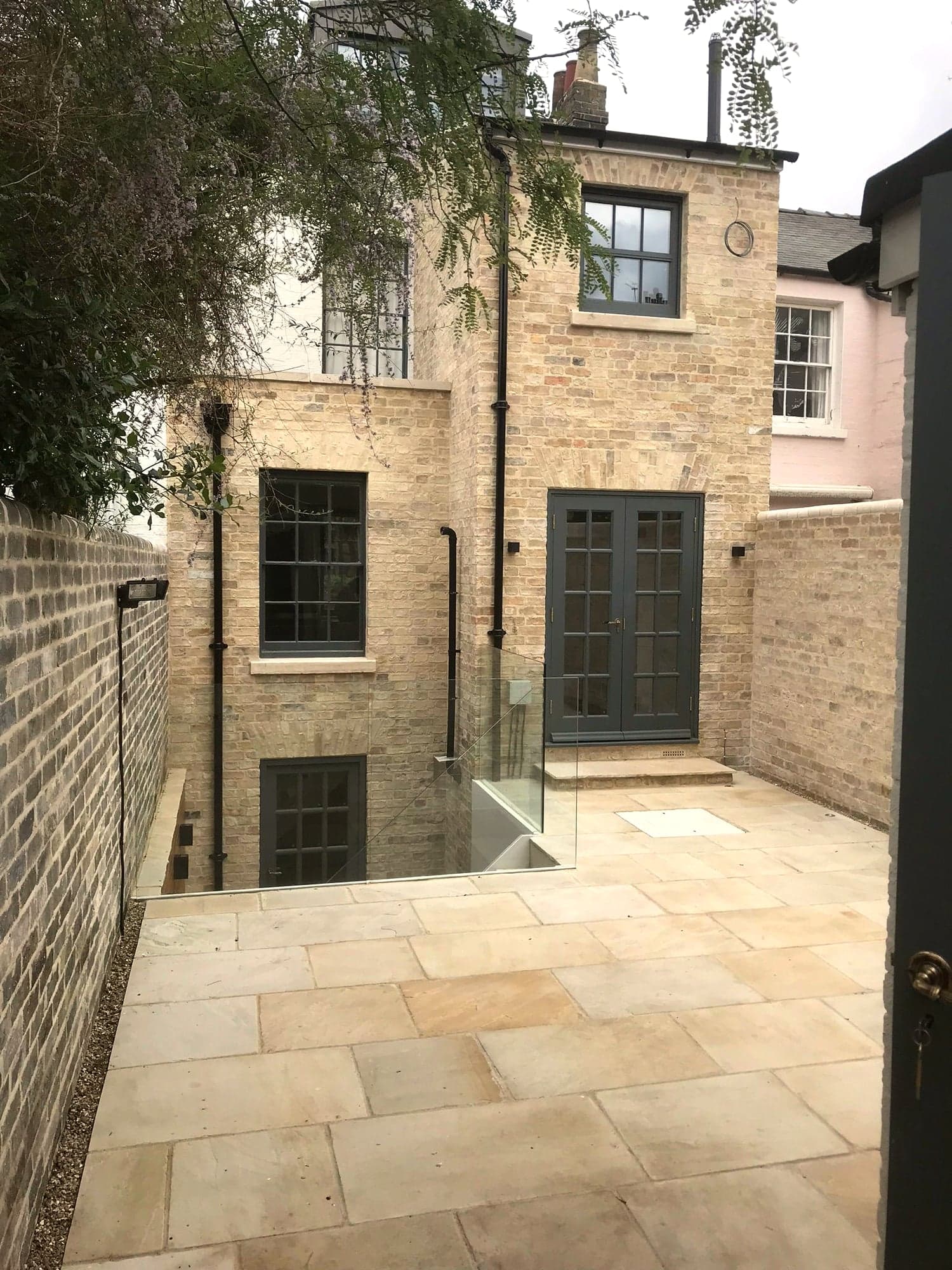 Rear elevation of the completed stone extension with the courtyard steps and glass balustrade, Kensington W8