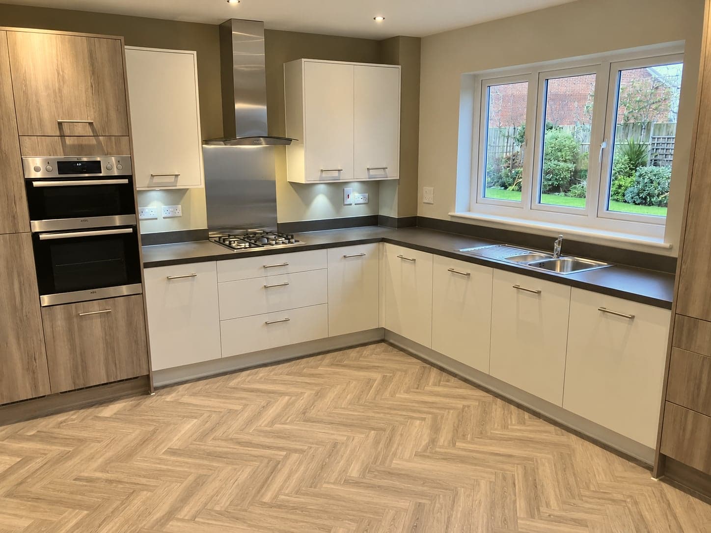 Kitchen from the dining end: oven tower, hob, extractor and sink run under the window, St Albans AL1