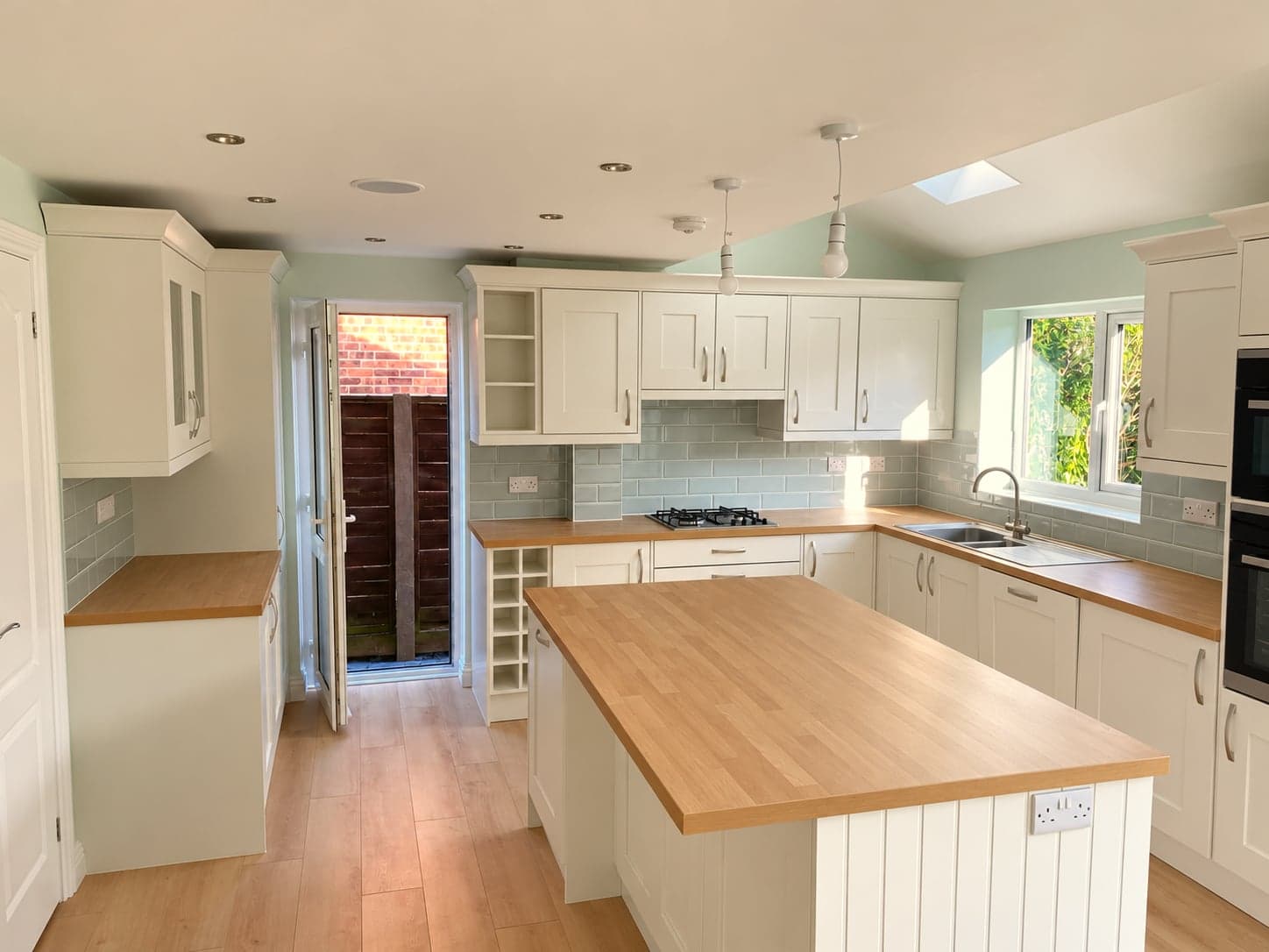 Finished shaker kitchen with oak-topped island, rooflight above and garden doors beyond, Borehamwood WD6
