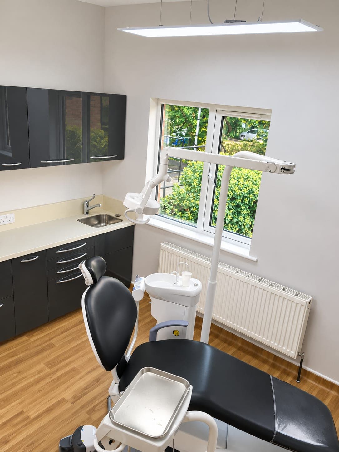Refurbished dental surgery with graphite cabinetry, dental chair and wood-effect flooring, Winchmore Hill N21