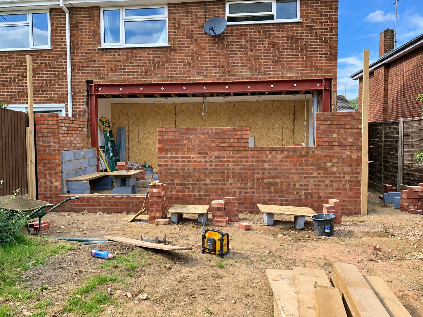 Red brick rear extension walls going up under a new steel opening, London